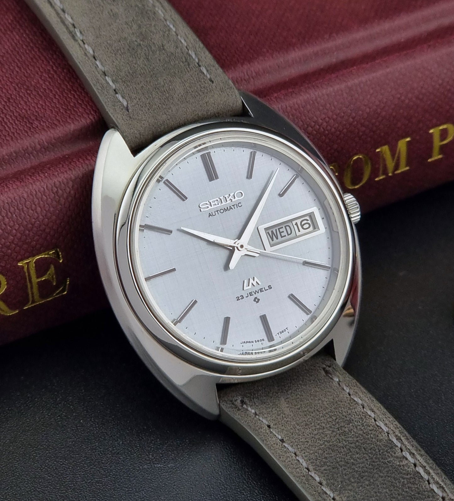 Seiko watch with gray leather strap on a dark surface