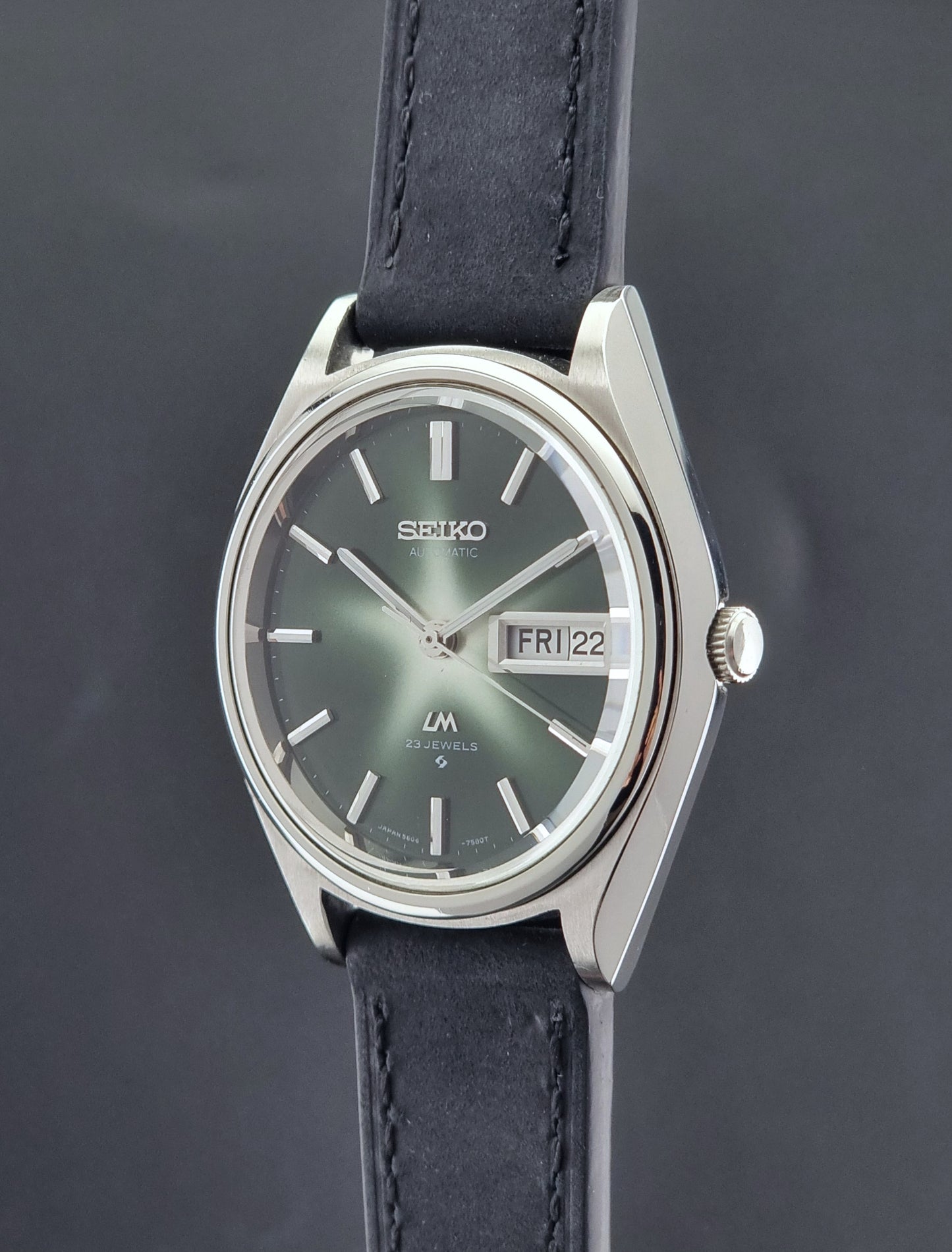 Seiko Lord Matic watch with a dark blue strap on a gray background