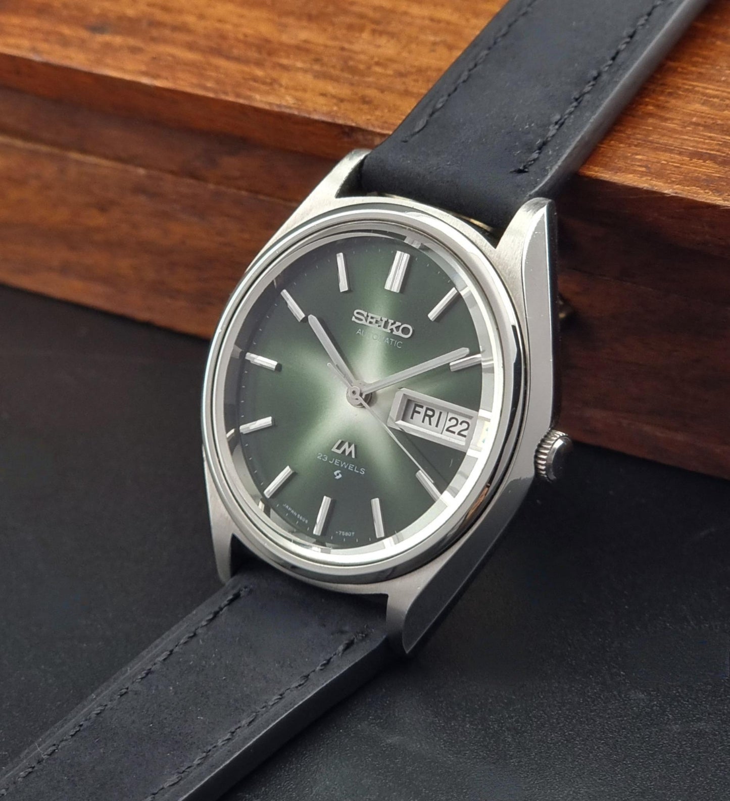 Vintage Seiko Lord Matic watch with black leather strap on a wooden surface
