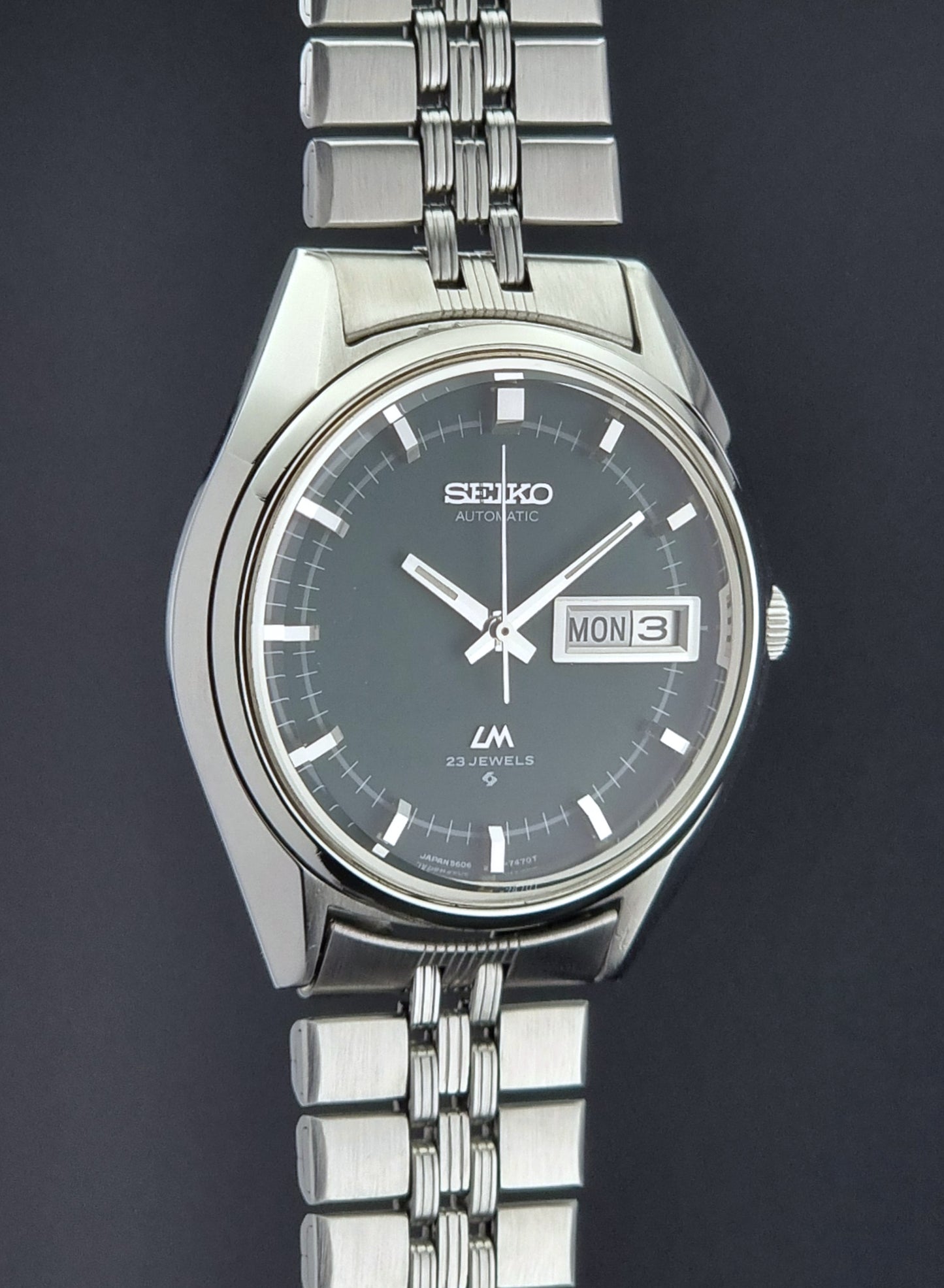 Silver Seiko watch with a dark face on a black background