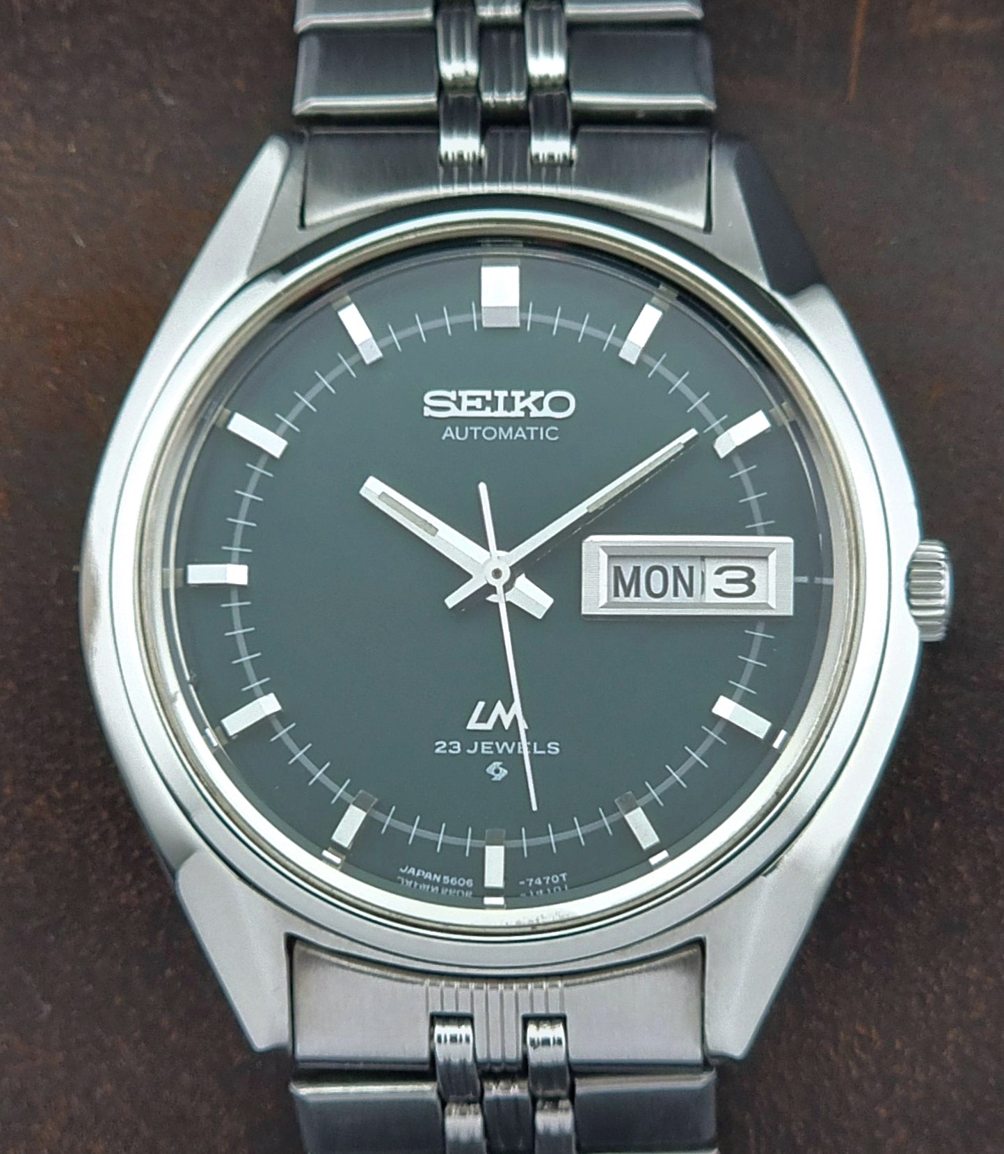 Seiko watch with silver metal strap on a dark background