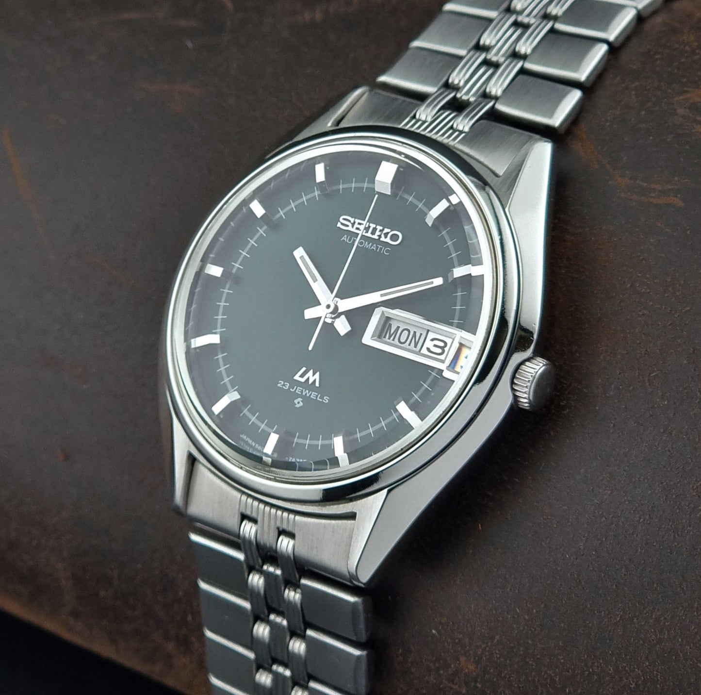 Seiko watch with silver metal strap on a dark background