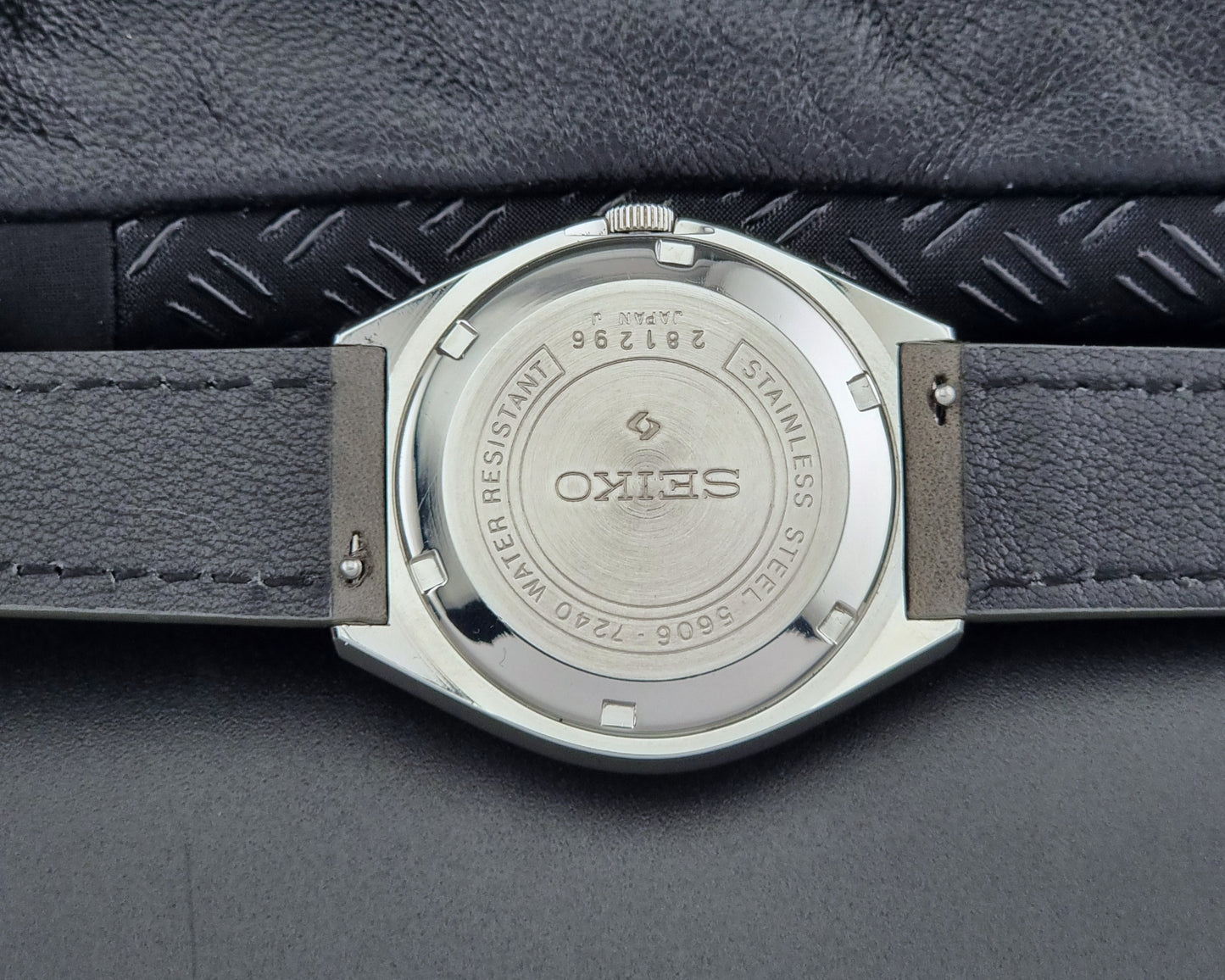 Close-up of a Seiko watch back with 'Stainless Steel' text on a textured gray background