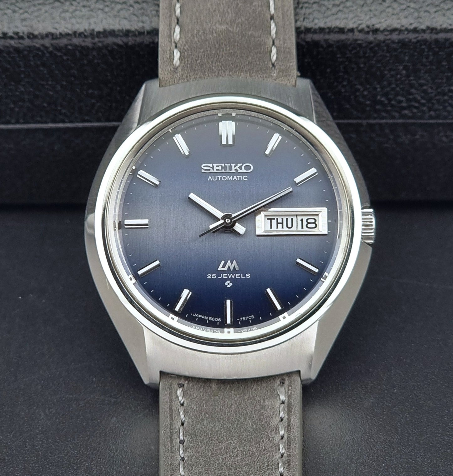 Vintage Seiko 5606-7240 watch with blue dial and gray leather strap on a dark background