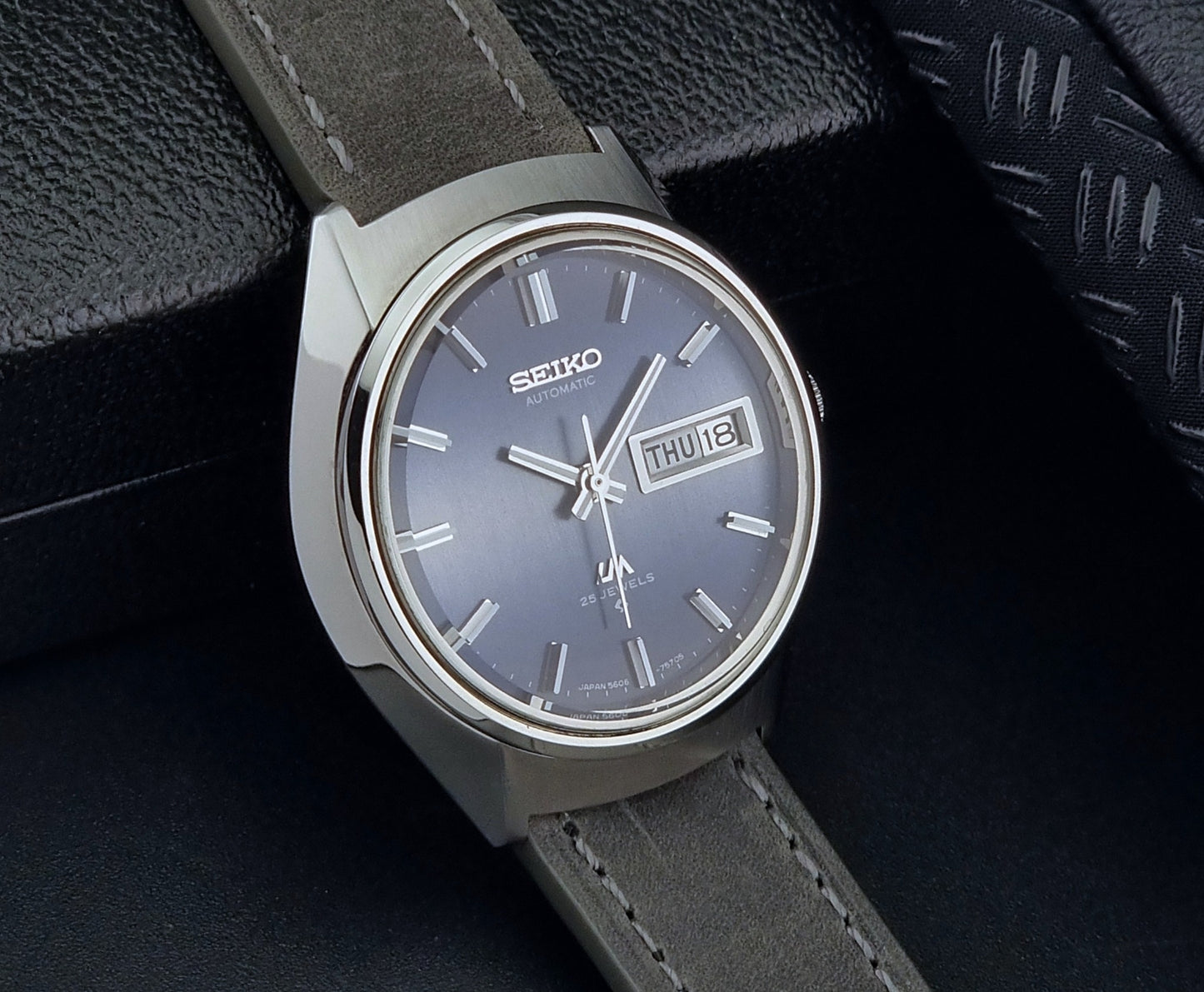 Vintage Seiko 5606-7240 watch with a dark blue face and gray strap on a black background