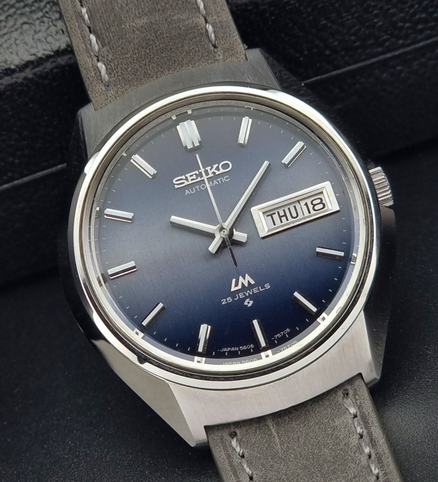 Vintage Seiko 5606-7240 watch with blue dial and gray leather strap on a dark background