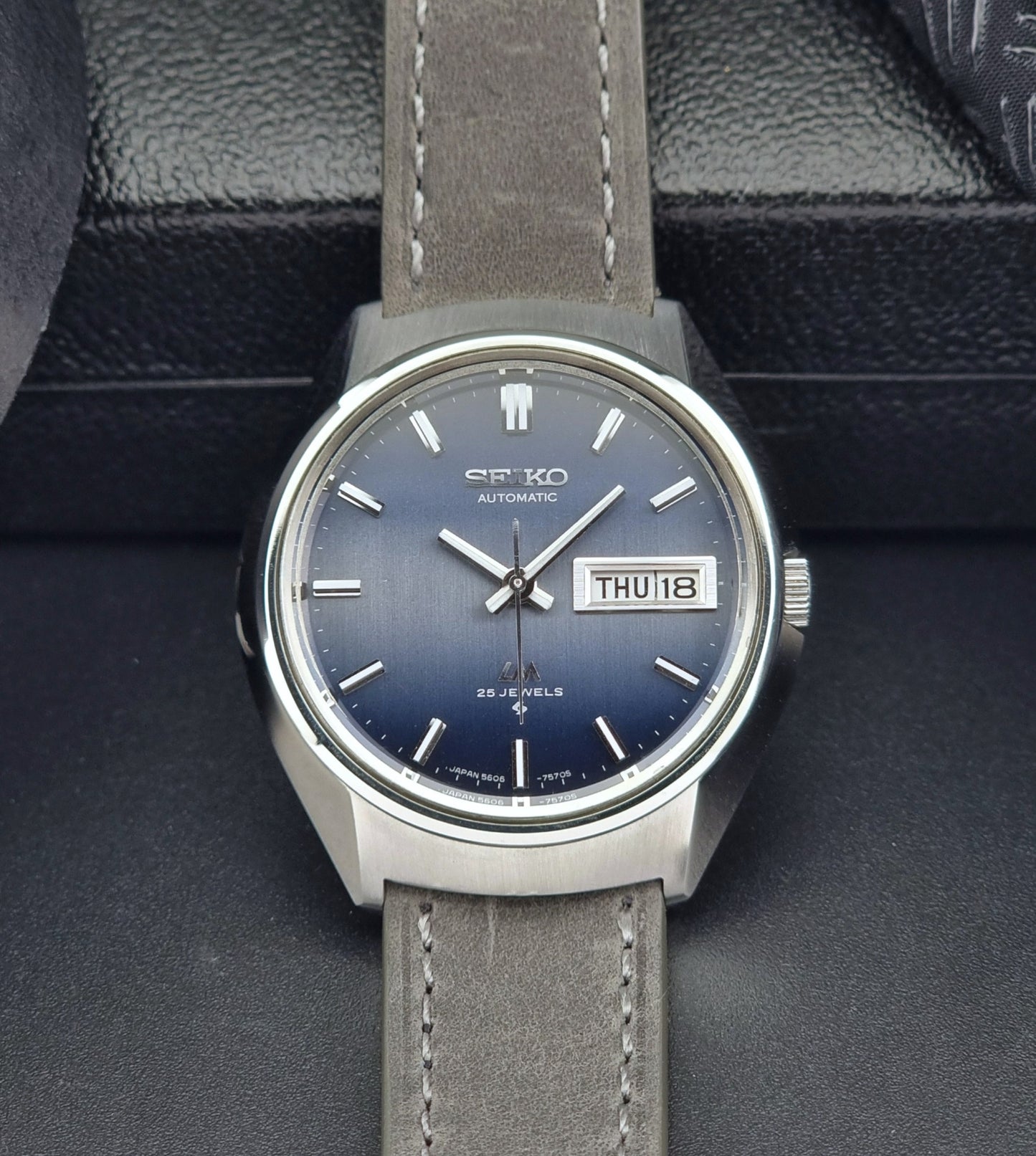 Vintage Seiko 5606-7240 watch with gray strap on a dark background