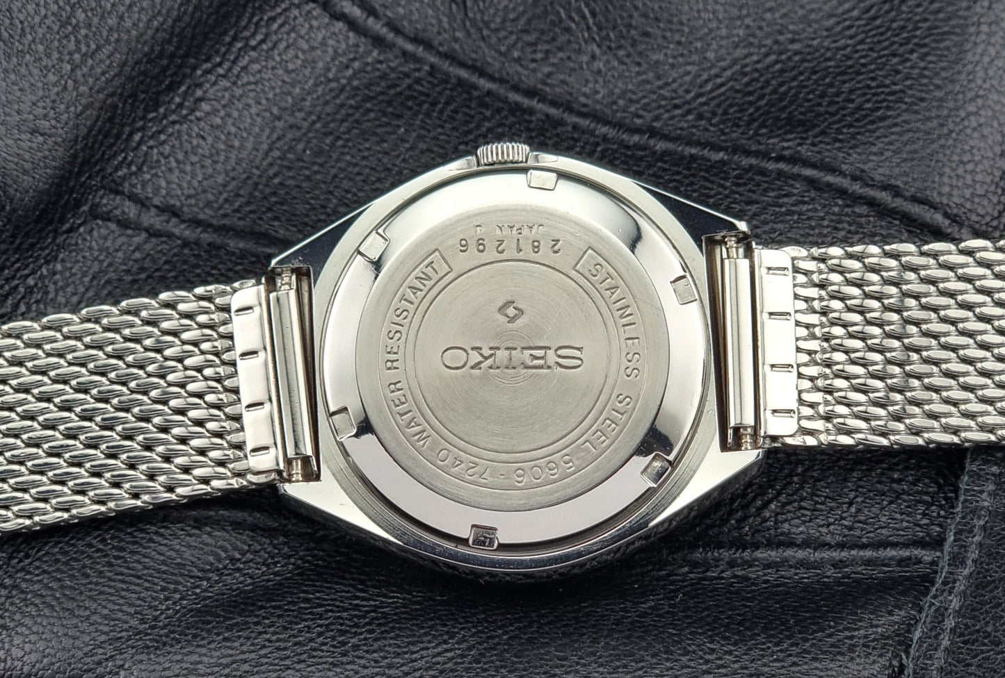 Close-up of a Seiko watch case back on a textured black surface