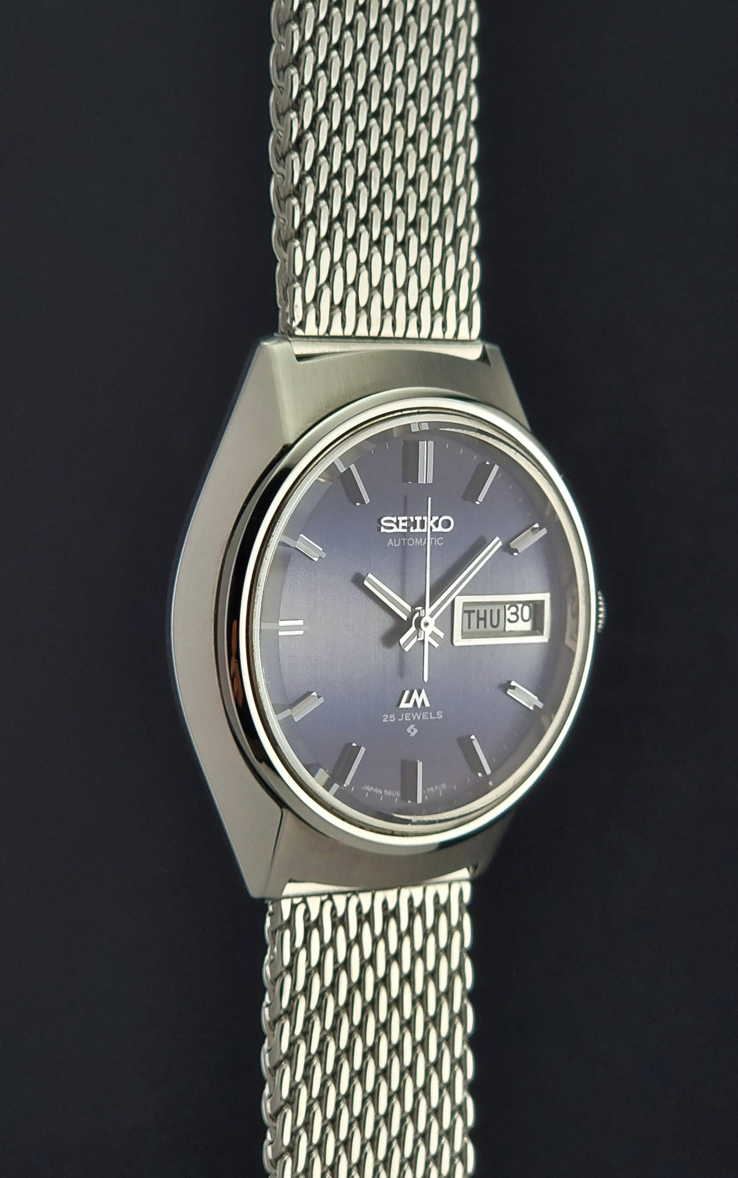 Seiko watch with silver mesh strap on a dark background