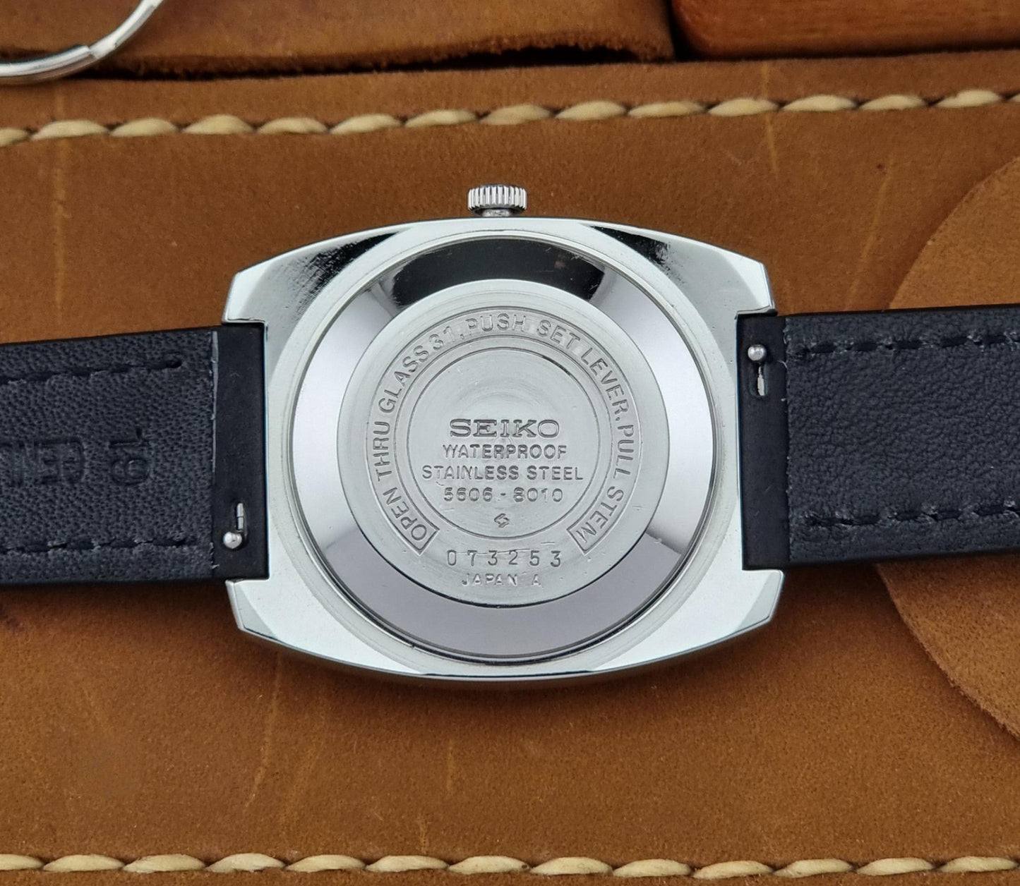 Seiko watch back view on a brown leather surface