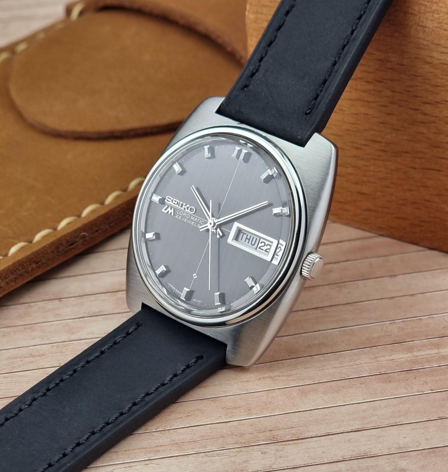Seiko Lord Matic watch with black leather strap on a wooden surface