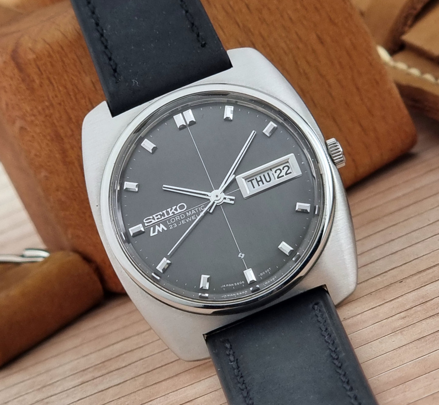 Seiko Lord Matic watch with black leather strap on a wooden surface