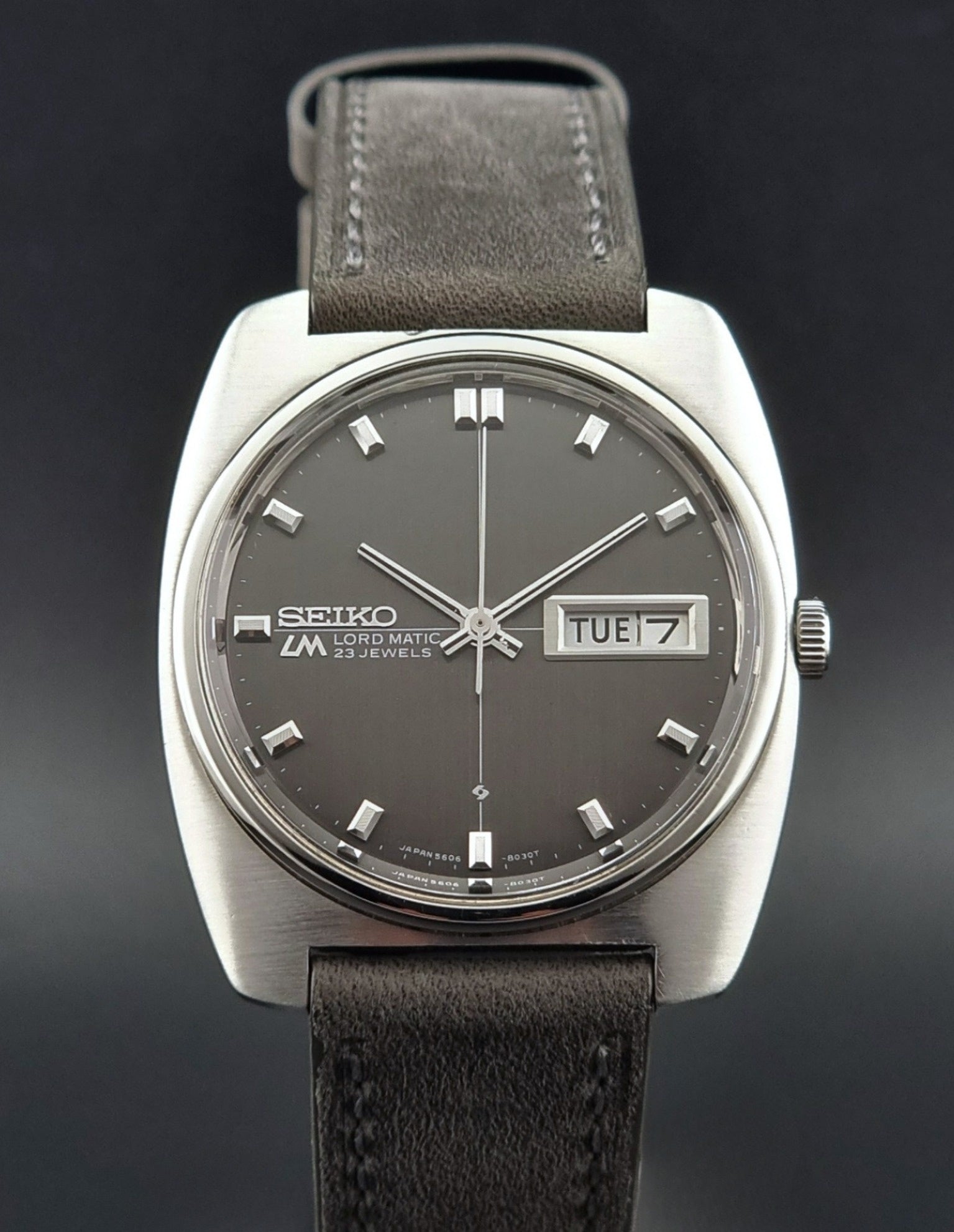 Vintage Seiko Lord Matic 5606-8010 watch with grey leather strap on a gray background close up