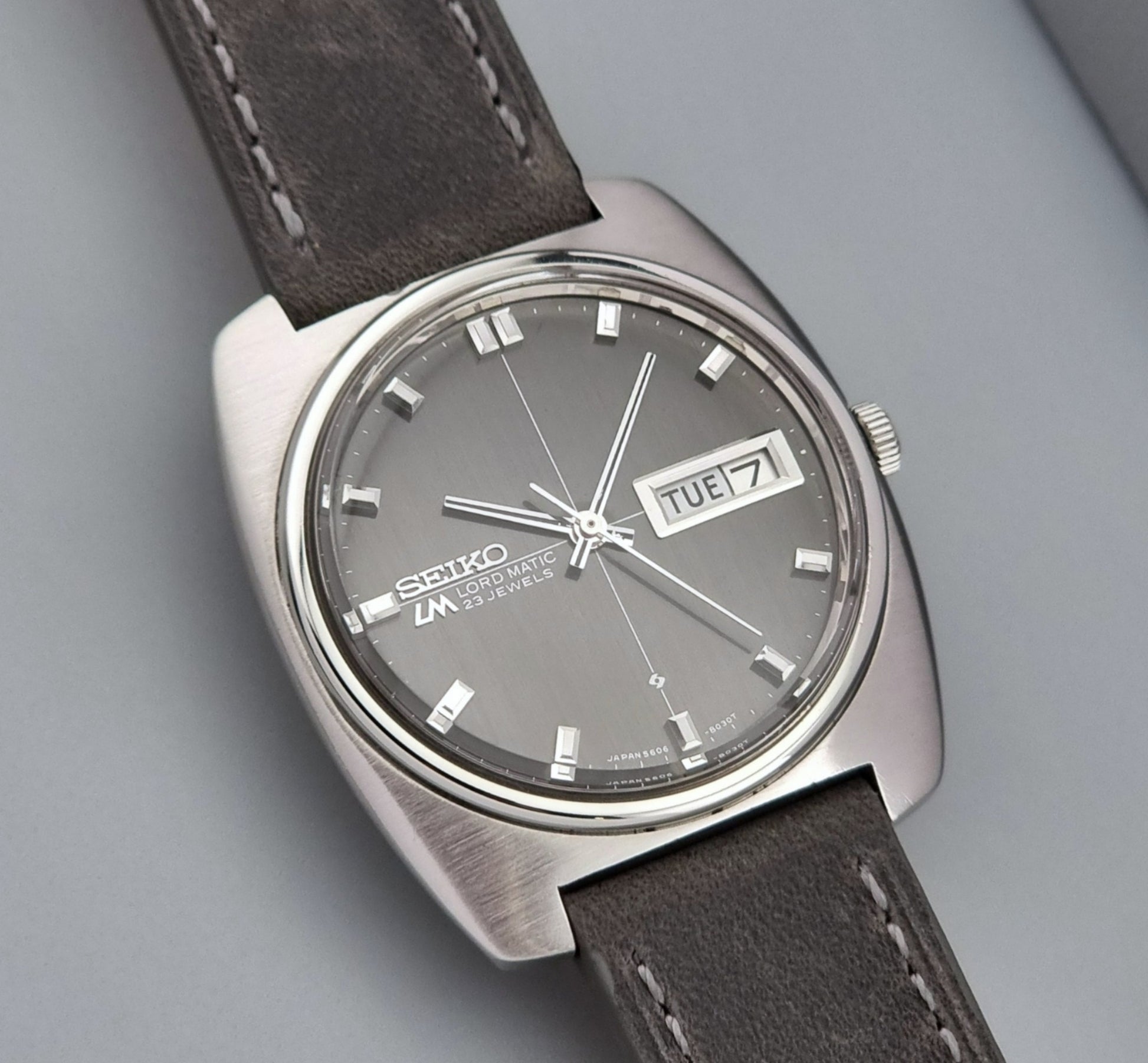 Vintage Seiko Lord Matic 5606-8010 watch with grey leather strap on a gray background close up front