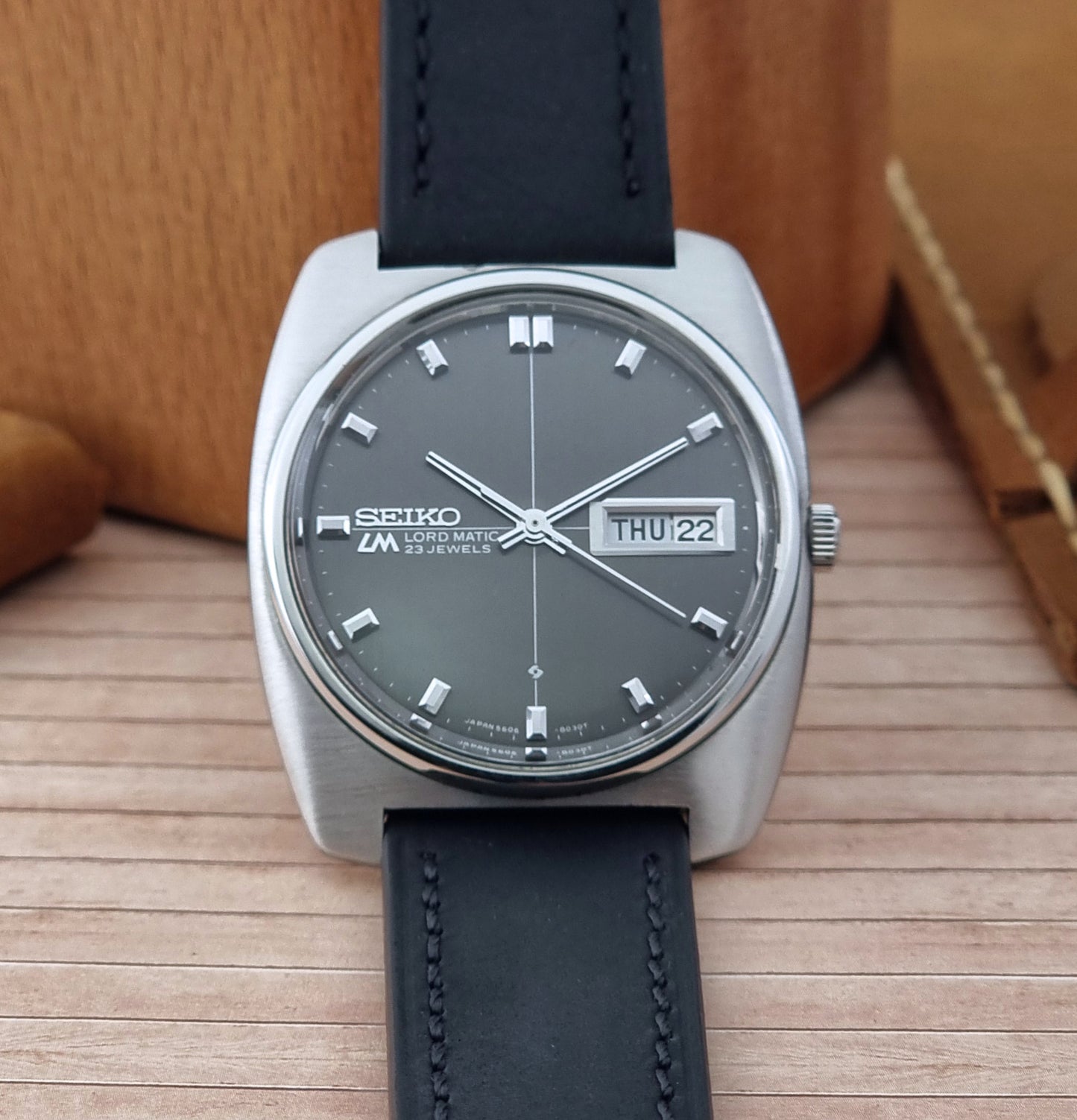 Seiko Lord Matic watch with black leather strap on a wooden surface
