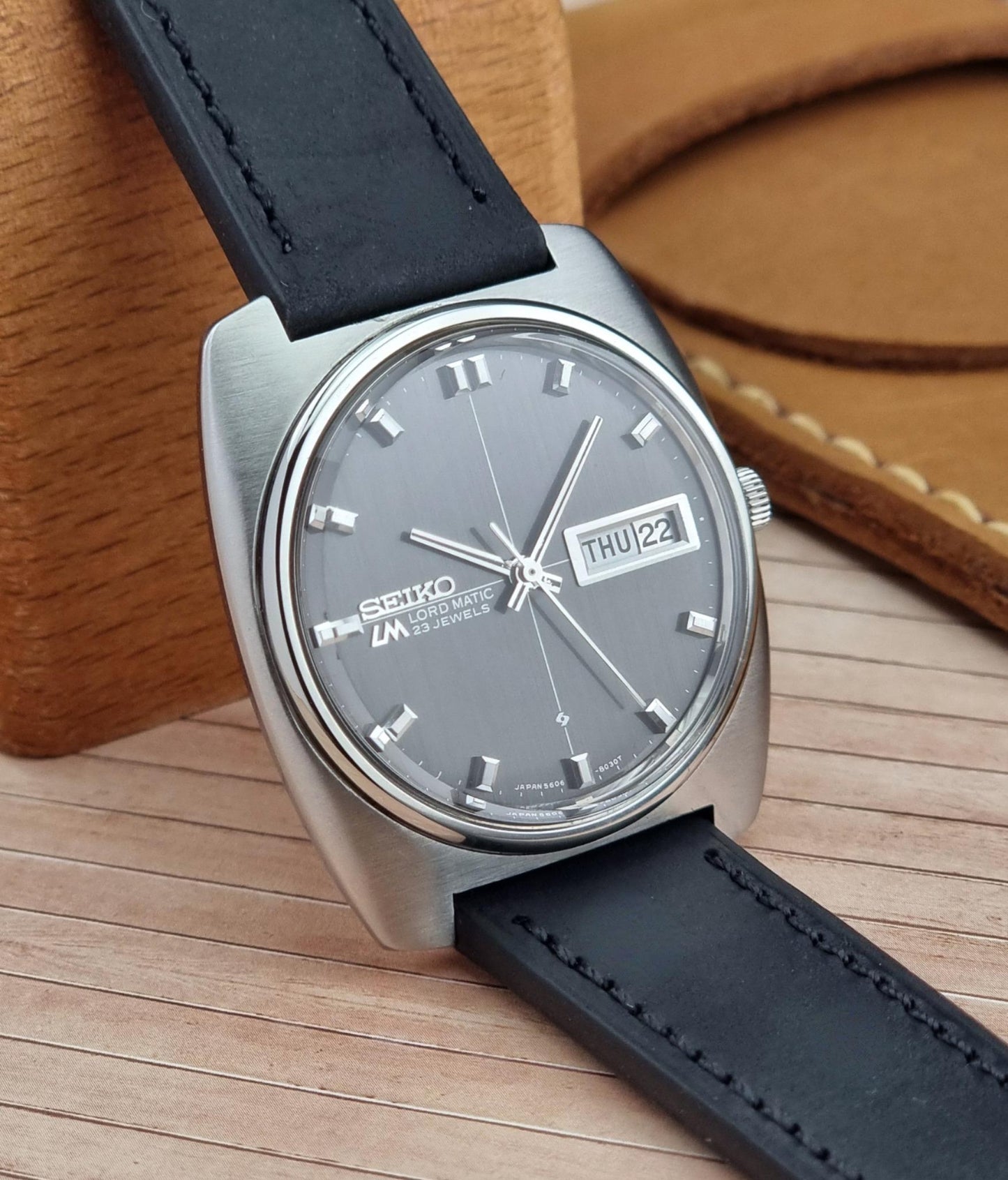 Seiko Lord Matic watch with black leather strap on a wooden surface