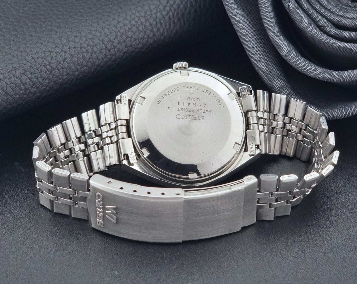 Vintage Seiko Wristwatch LordMatic 5606-8030 with blue gradient dial on a dark textured surface case back view