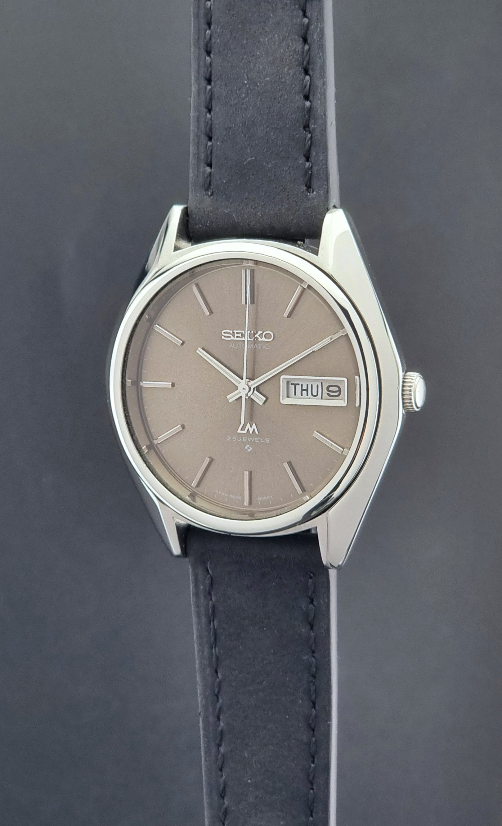 Vintage Seiko Lordmatic 5606-8031 watch with a brown dial and a dark strap crown side profile
