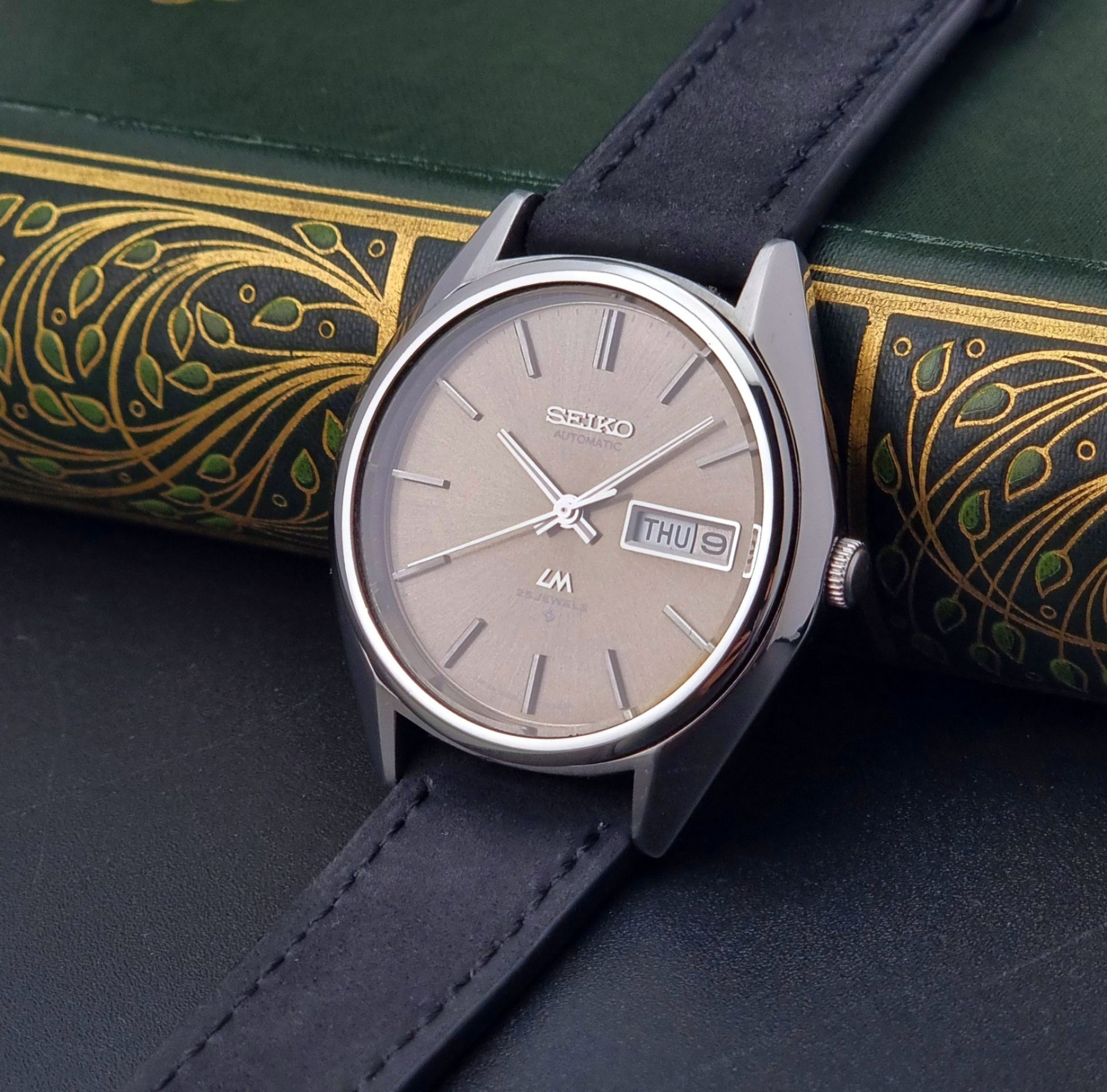 Vintage Seiko Lordmatic 5606-8031 watch with a brown dial and a dark strap the crown side view