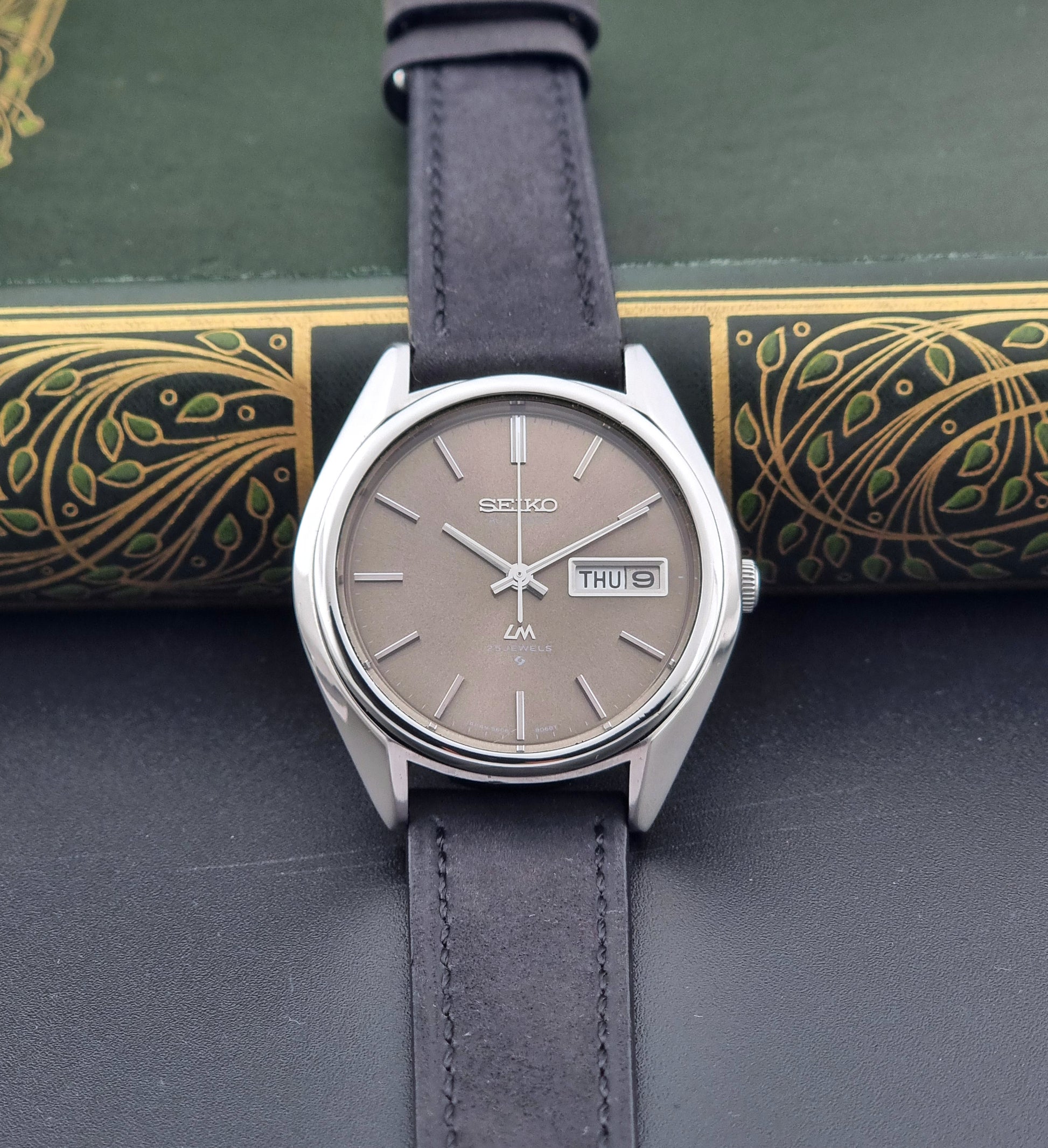 Vintage Seiko Lordmatic 5606-8031 watch with a brown dial and a dark strap a front view