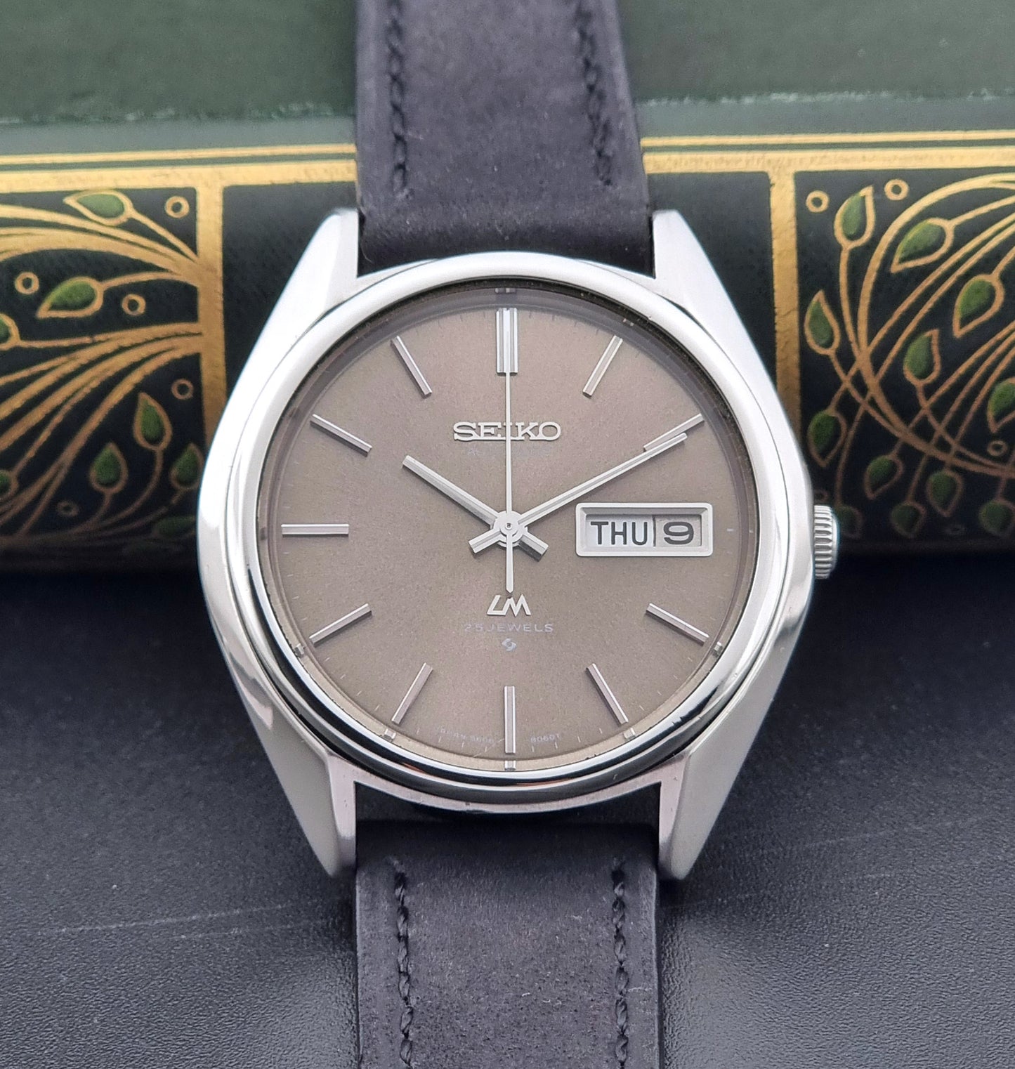 Vintage Seiko Lordmatic 5606-8031 watch with a brown dial and a dark strap close up of the dial