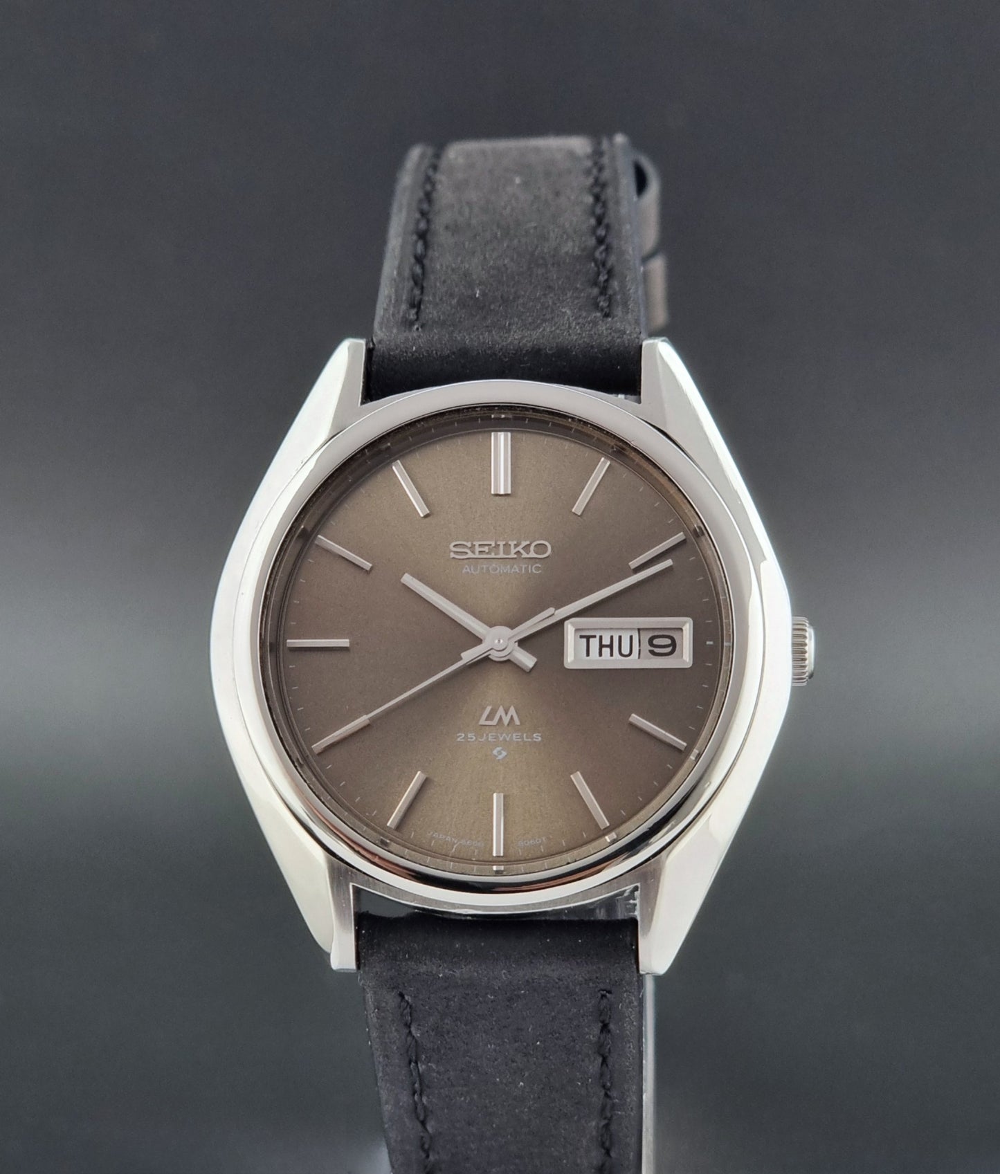 Vintage Seiko Lordmatic 5606-8031 watch with a brown dial and a dark strap a close up front view