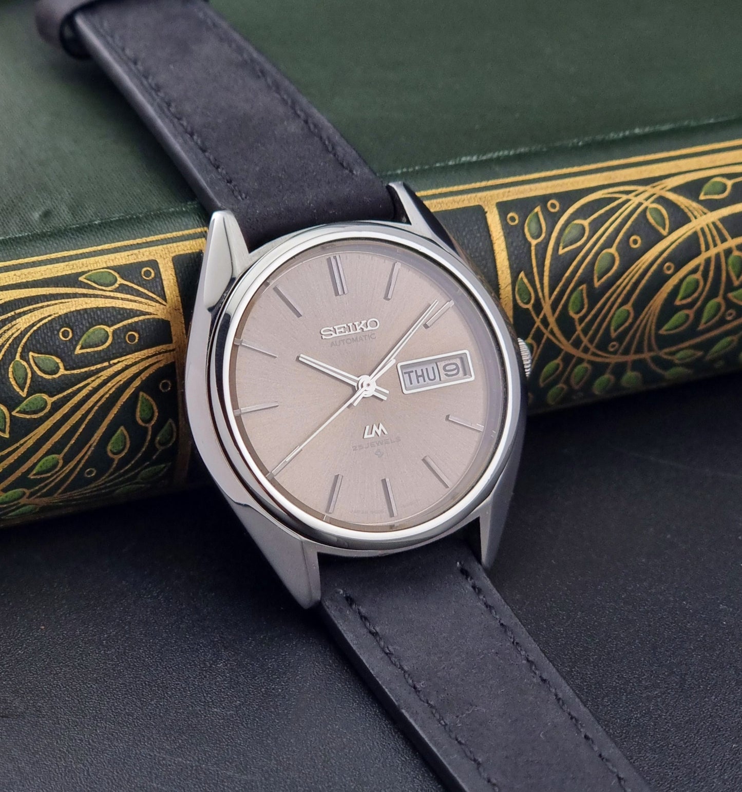 Vintage Seiko Lordmatic 5606-8031 watch with a brown dial and a dark strap a side view