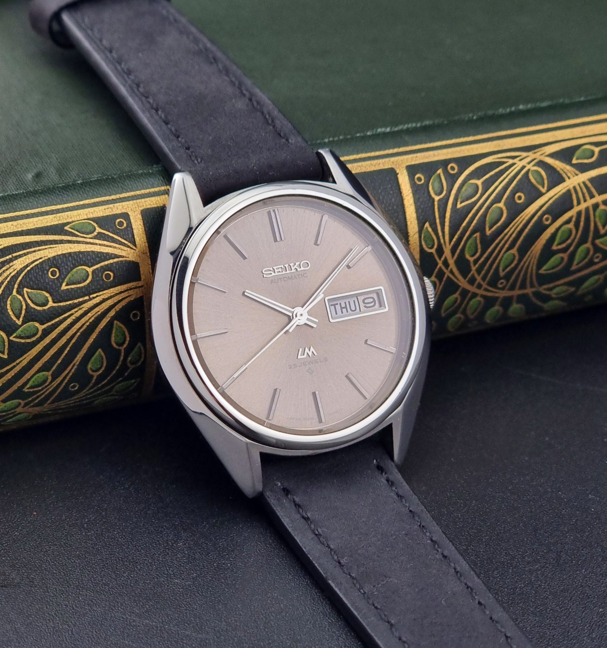 Vintage Seiko Lordmatic 5606-8031 watch with a brown dial and a dark strap a side view