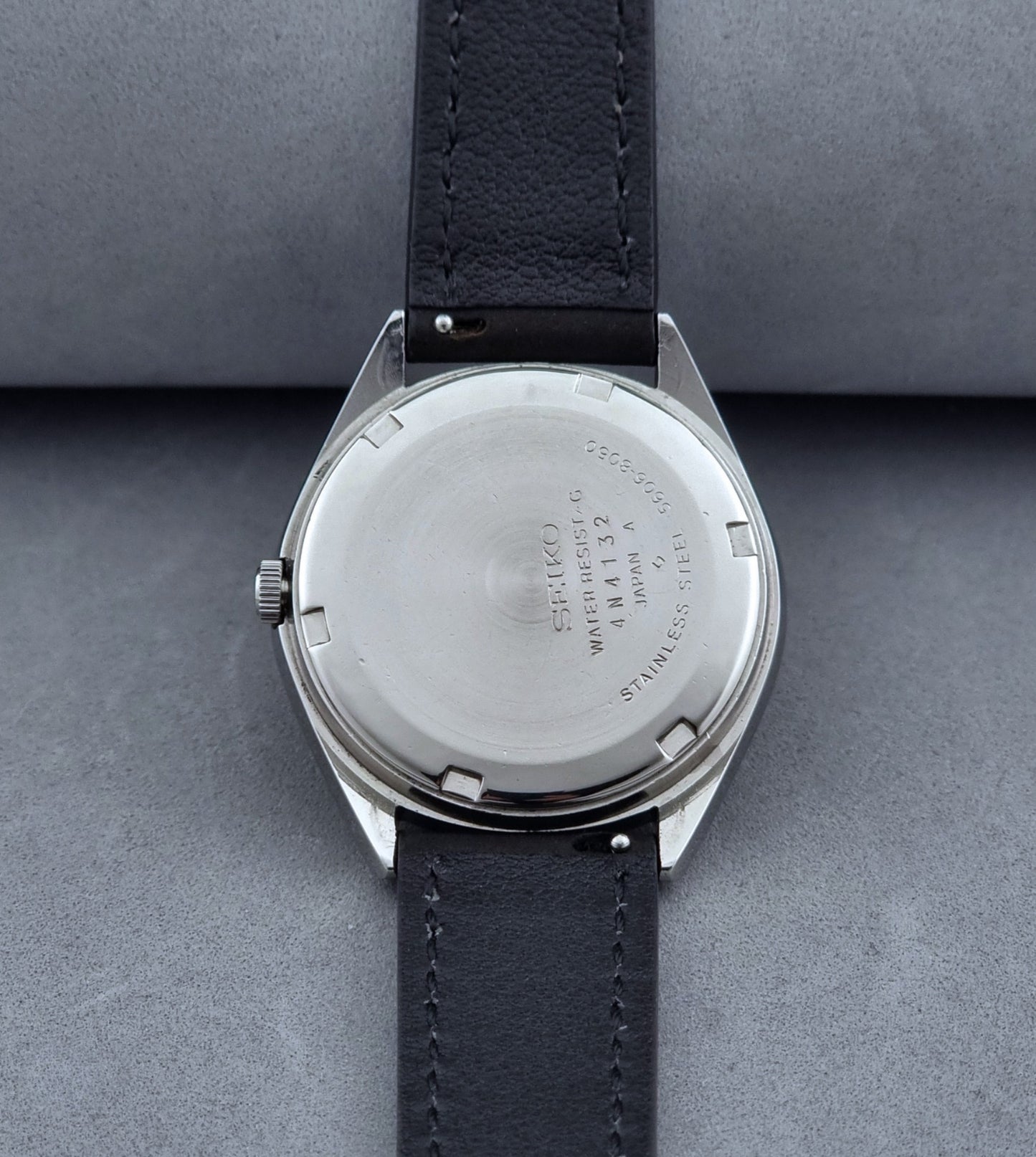 Vintage Seiko Wristwatch LordMatic 5606-8050 with blue gradient dial on a dark surface case back view