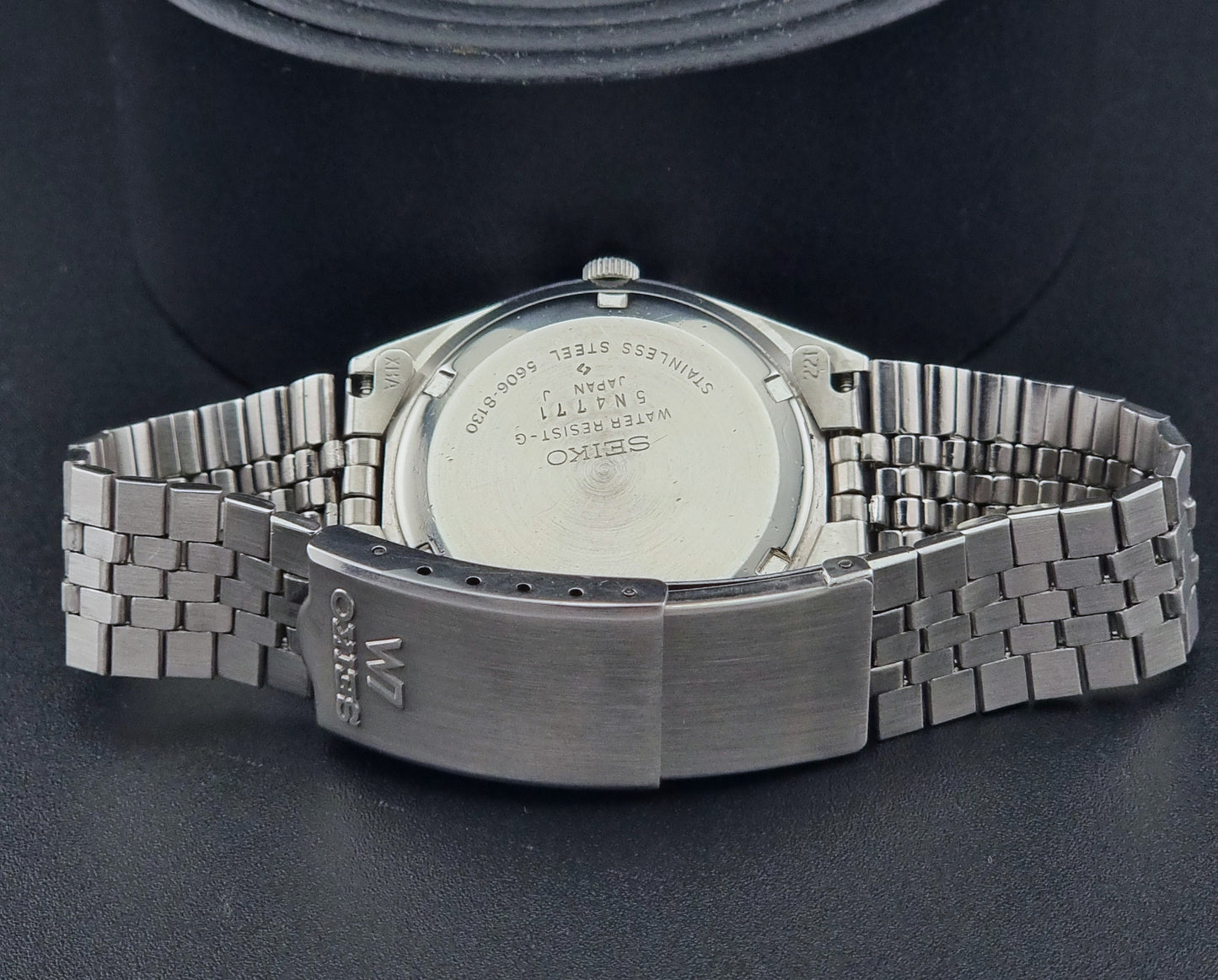 Vintage Seiko Lord Matic 56206-8130 watch with green face and silver metal strap on a dark textured background bracelet view