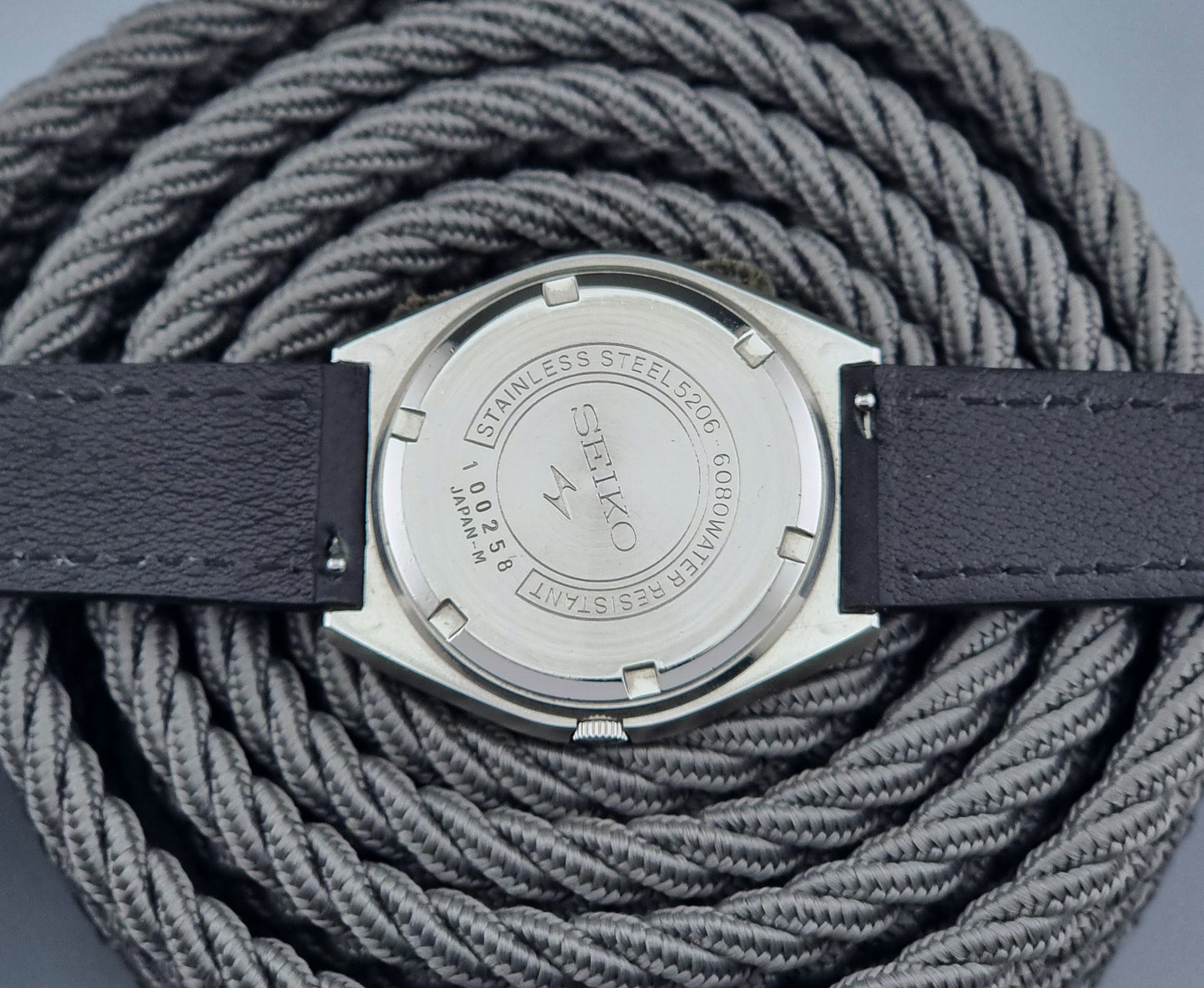 Vintage Seiko Lord Matic Special 5206-6080 watch with black leather strap on a gray background case back