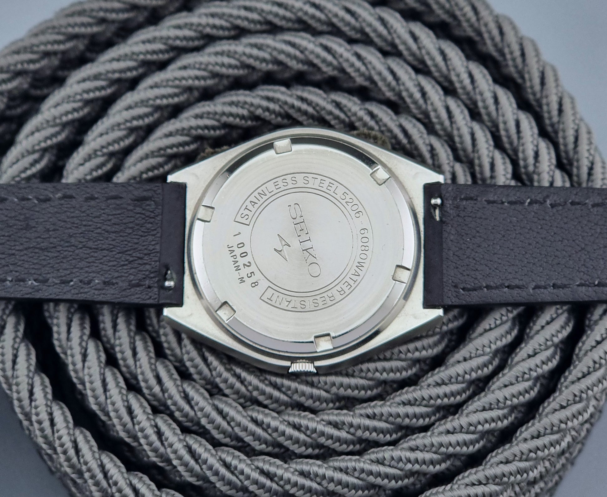 Vintage Seiko Lord Matic Special 5206-6080 watch with black leather strap on a gray background case back