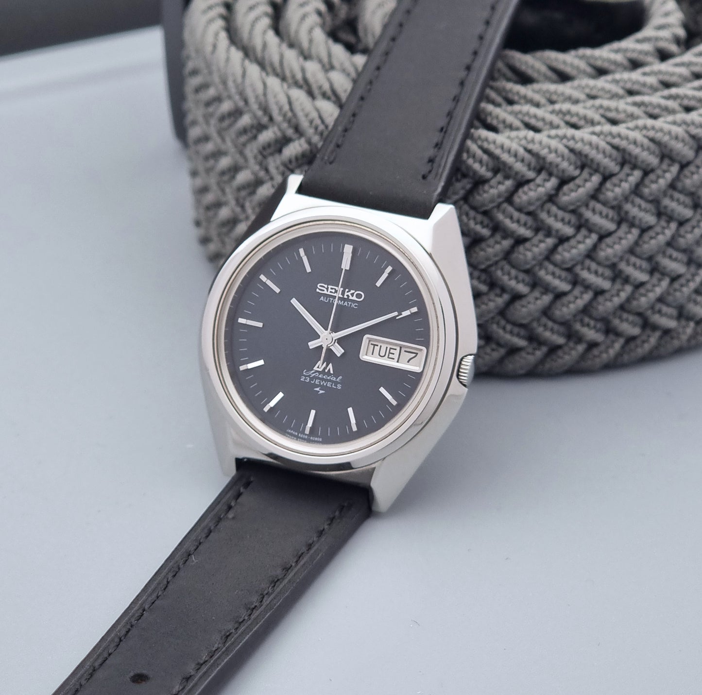 Vintage Seiko Lord Matic Special 5206-6080 watch with black leather strap on a gray background crown view
