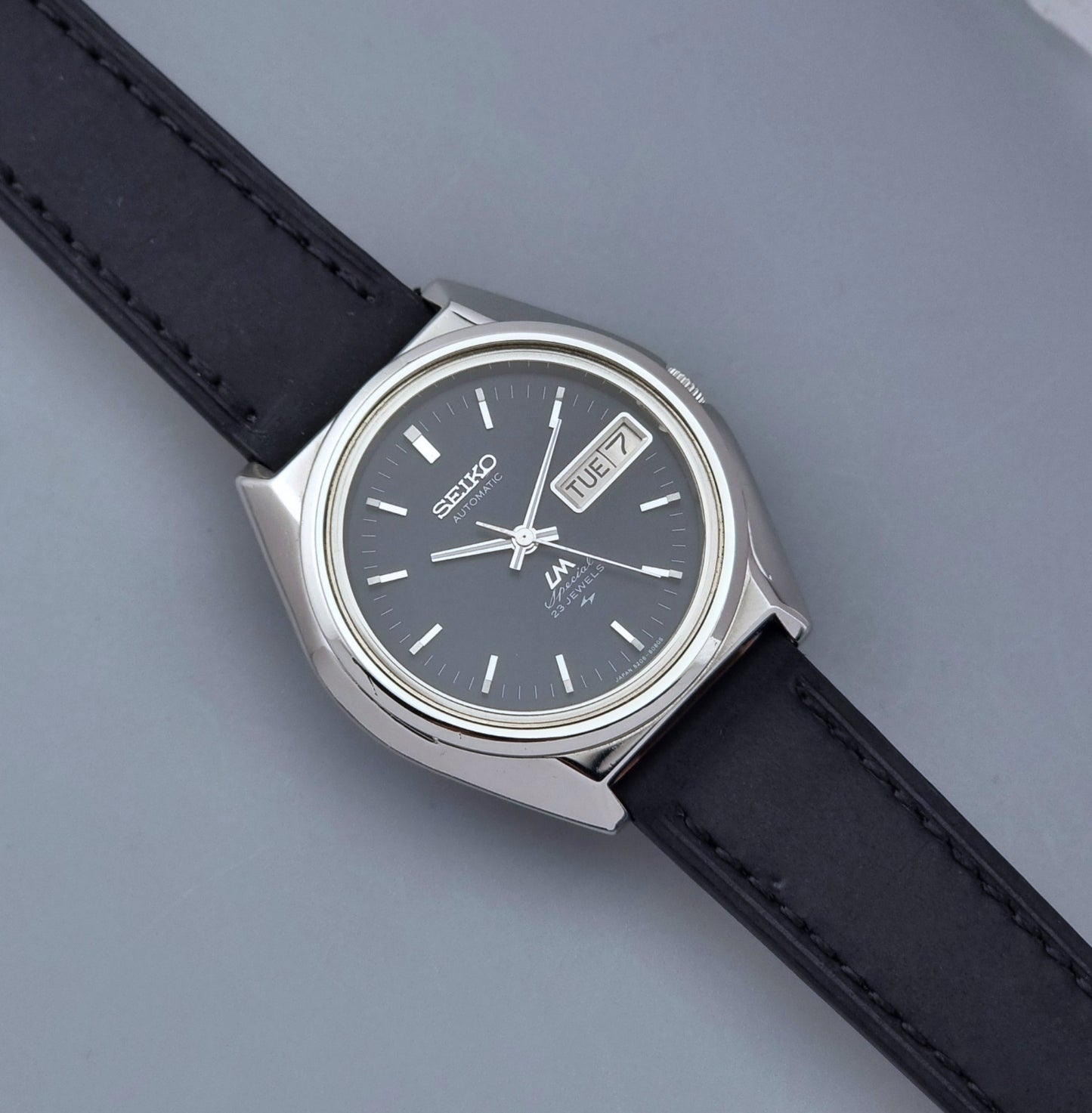 Vintage Seiko Lord Matic Special 5206-6080 watch with black leather strap on a gray background