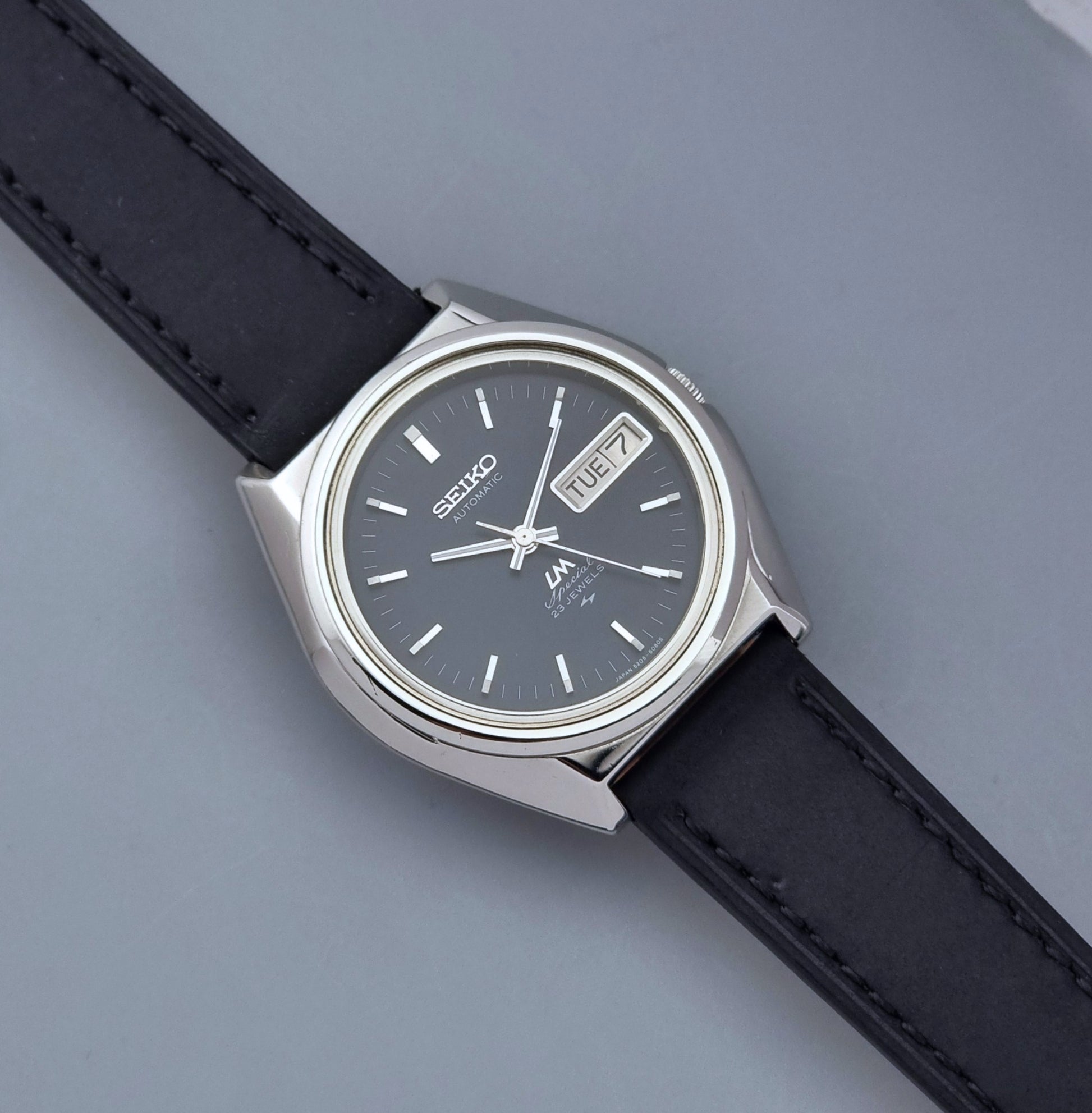 Vintage Seiko Lord Matic Special 5206-6080 watch with black leather strap on a gray background