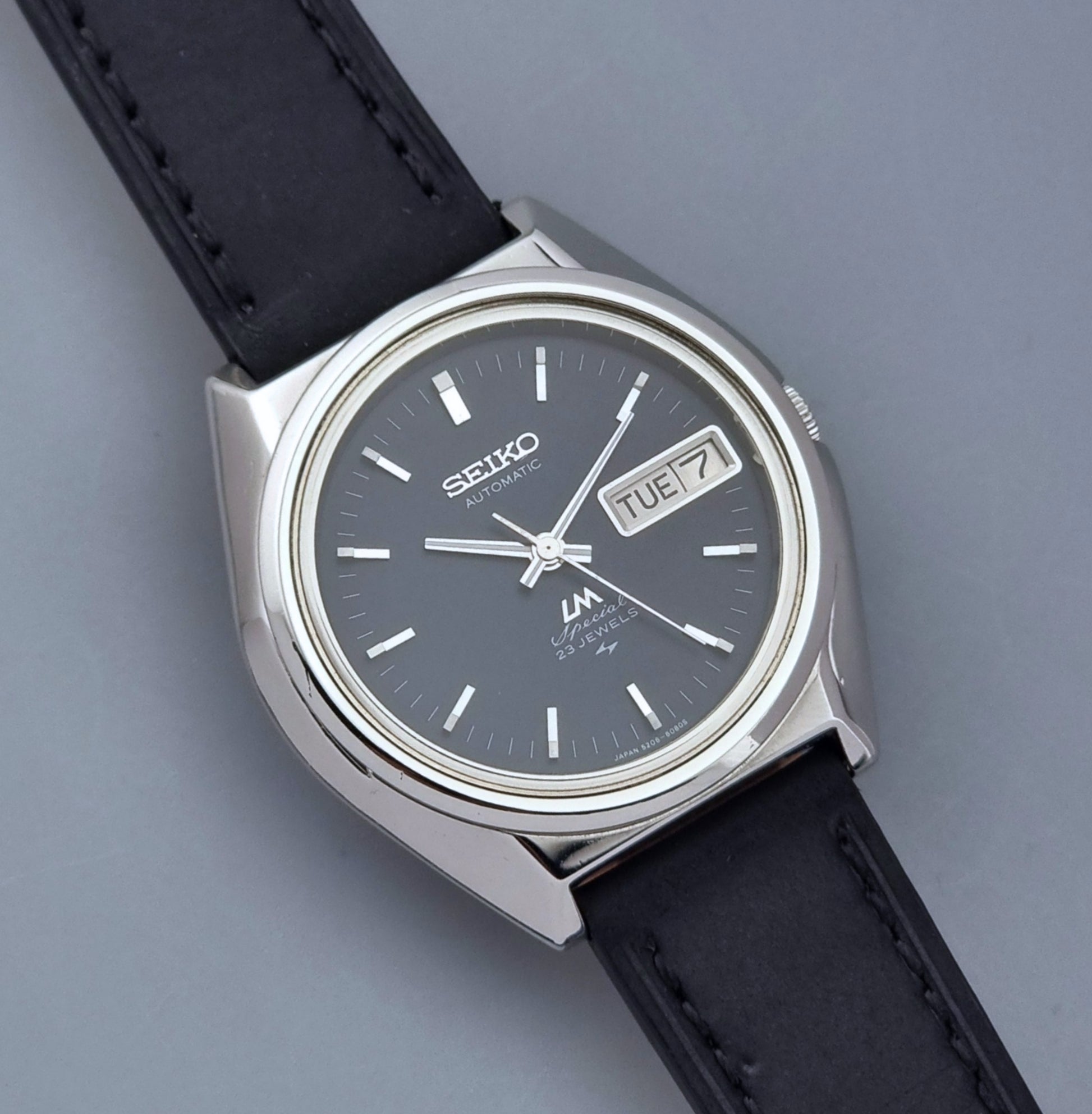 Vintage Seiko Lord Matic Special 5206-6080 watch with black leather strap on a gray background close up dial