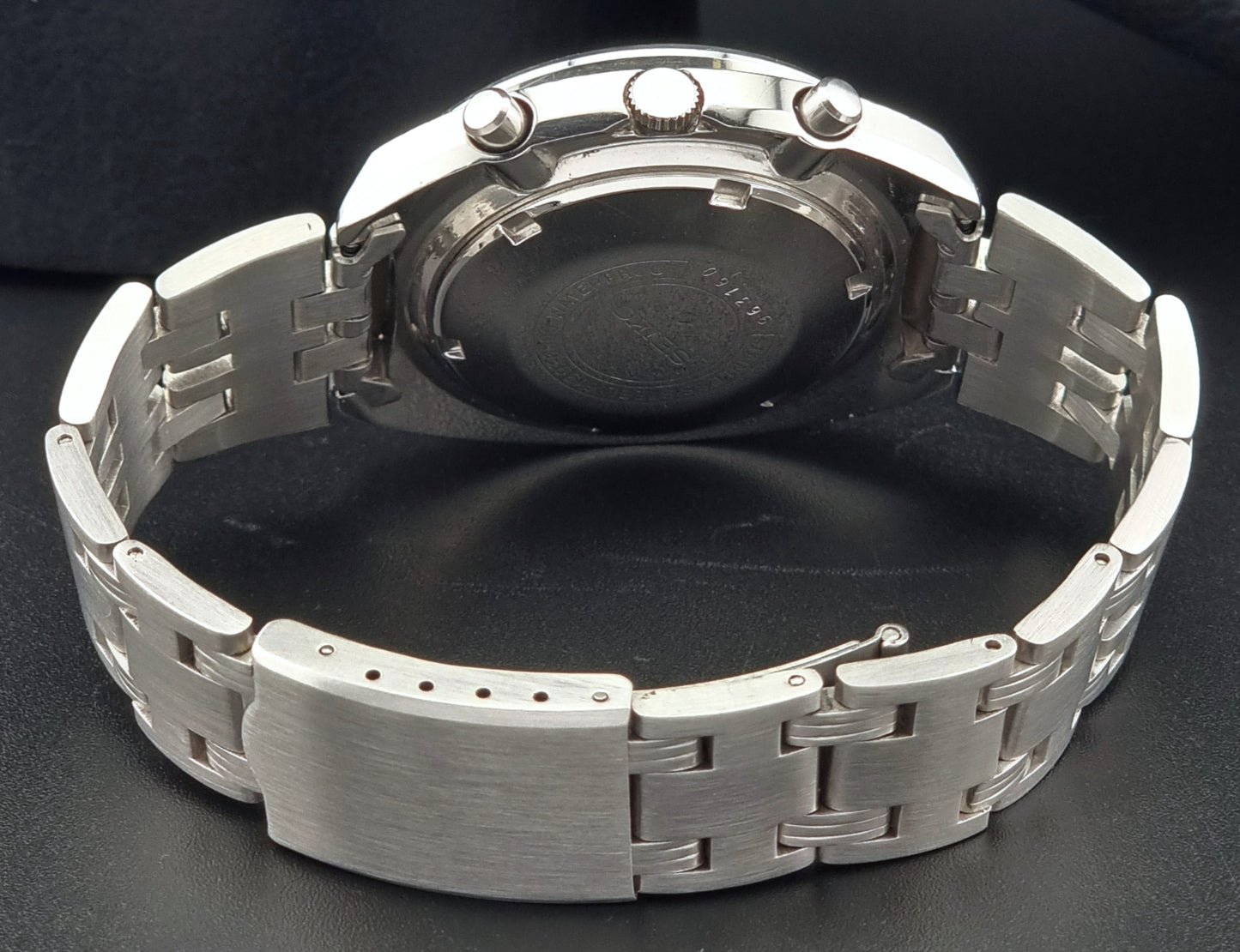 Seiko speedtimer watch case back and metal bracelet on a dark background