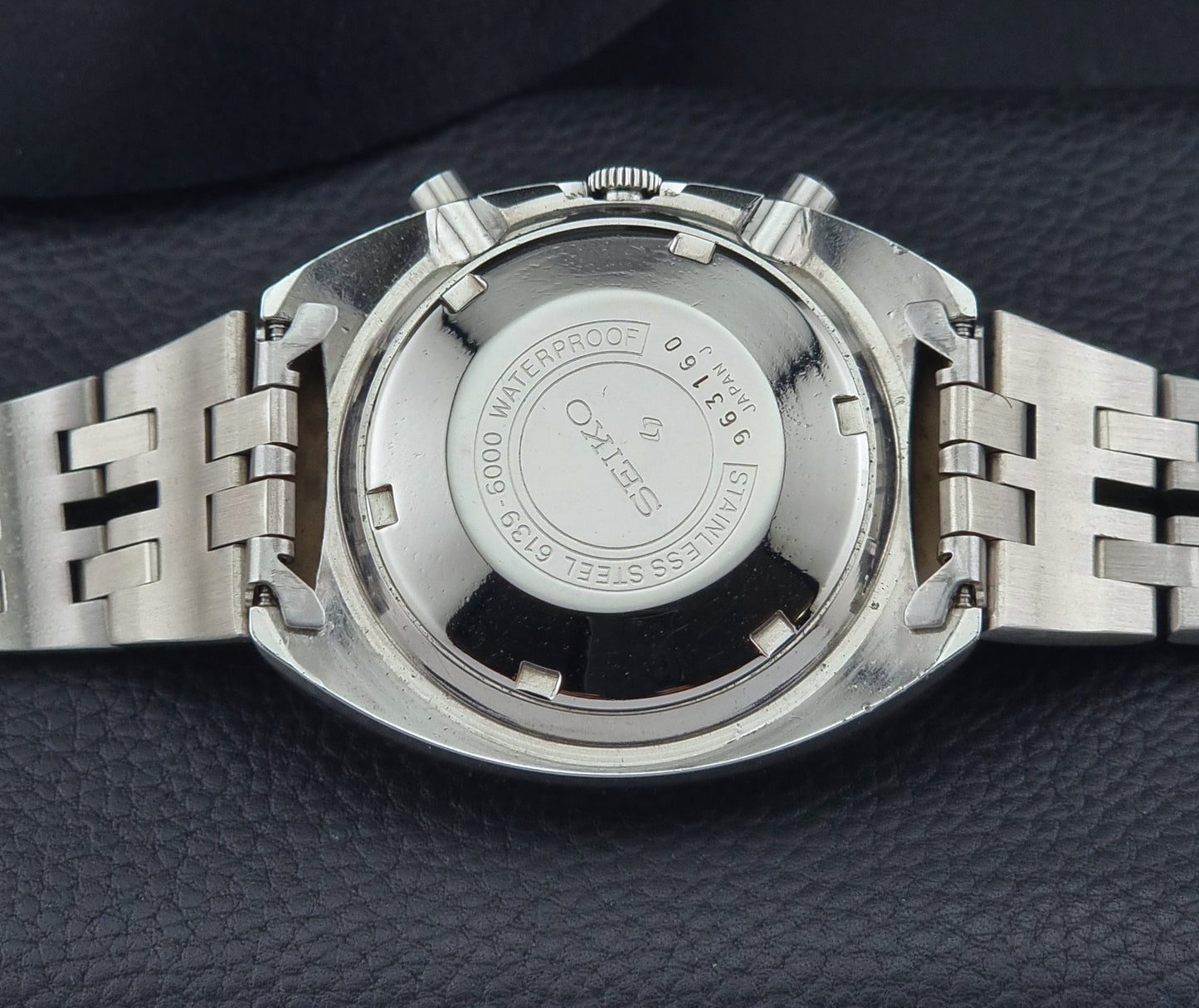 Close-up of a silver watch with Seiko branding on a dark textured surface