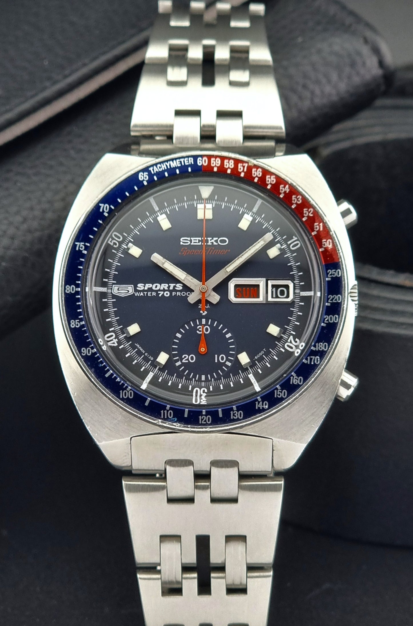 Seiko watch with a blue face and silver metal strap on a dark background