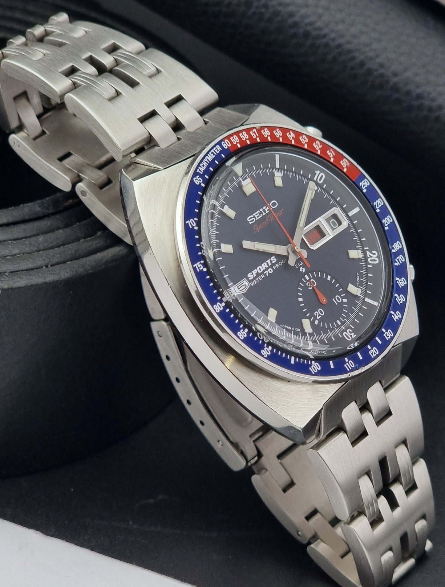 Seiko speedtimer watch with a silver metal strap on a dark background