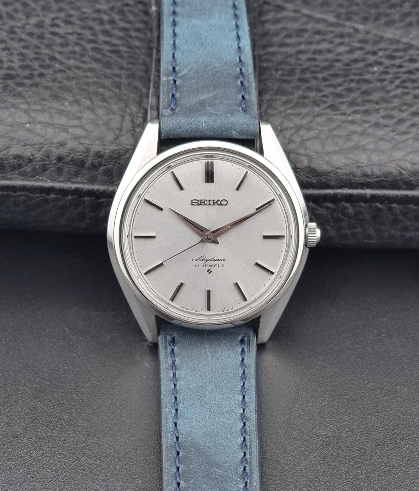 Seiko Skyliner 6100-8000 watch with a blue strap on a gray textured background