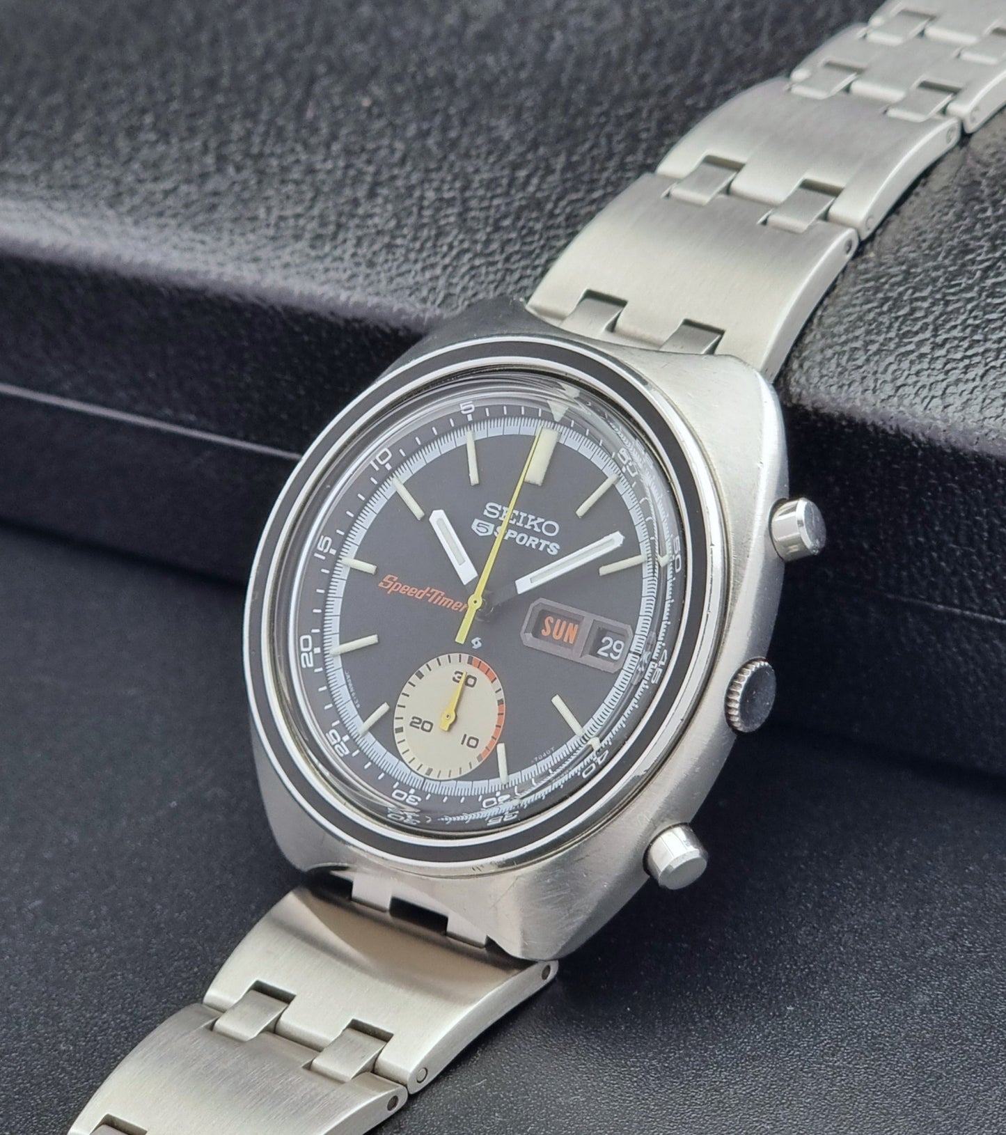 Vintage Seiko 5 sports Speedtimer 6139-7020 wristwatch with a dark face on a textured black background crown view