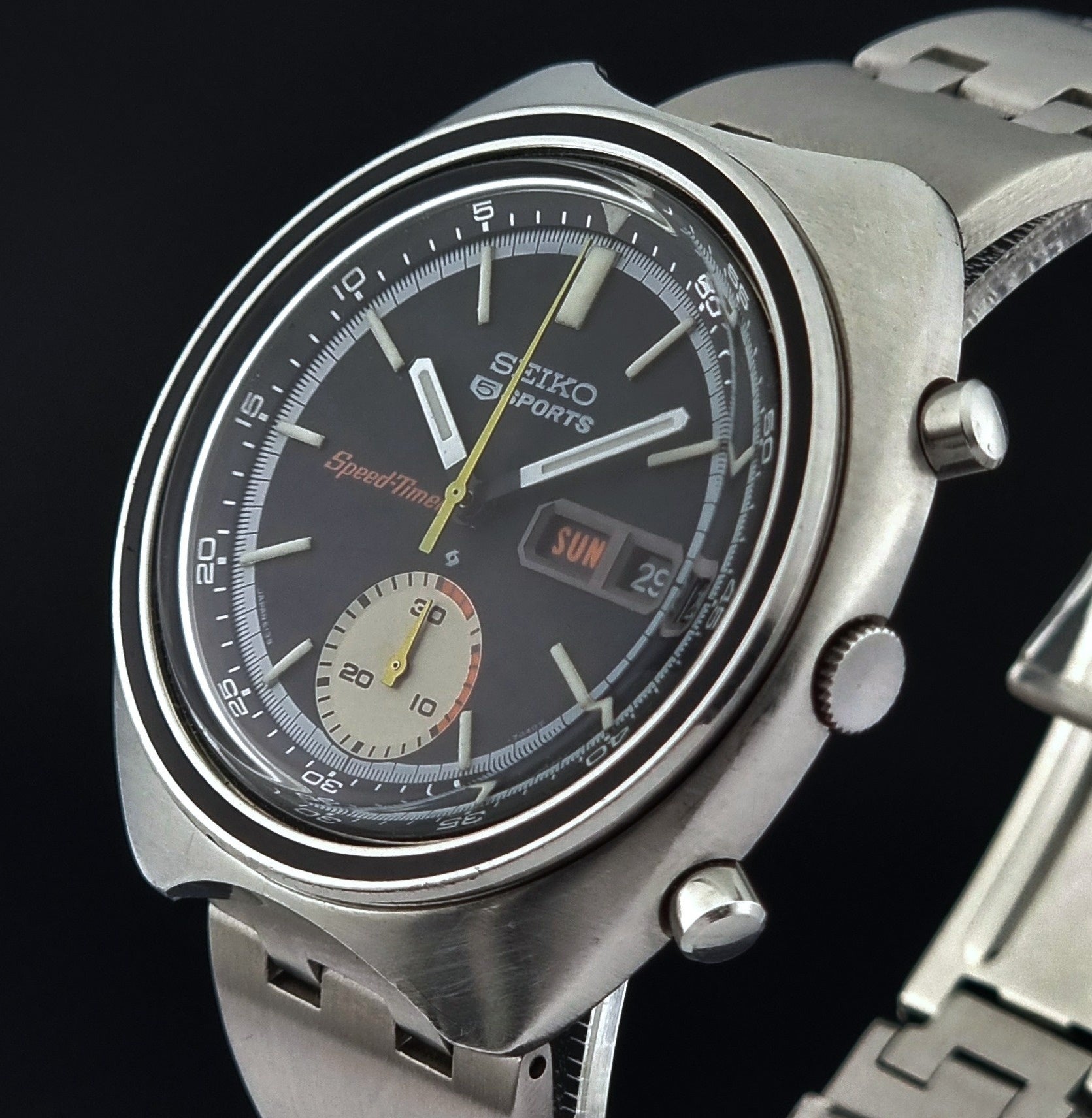 Vintage Seiko 5 sports Speedtimer 6139-7020 wristwatch with a dark face on a textured black background crown profile