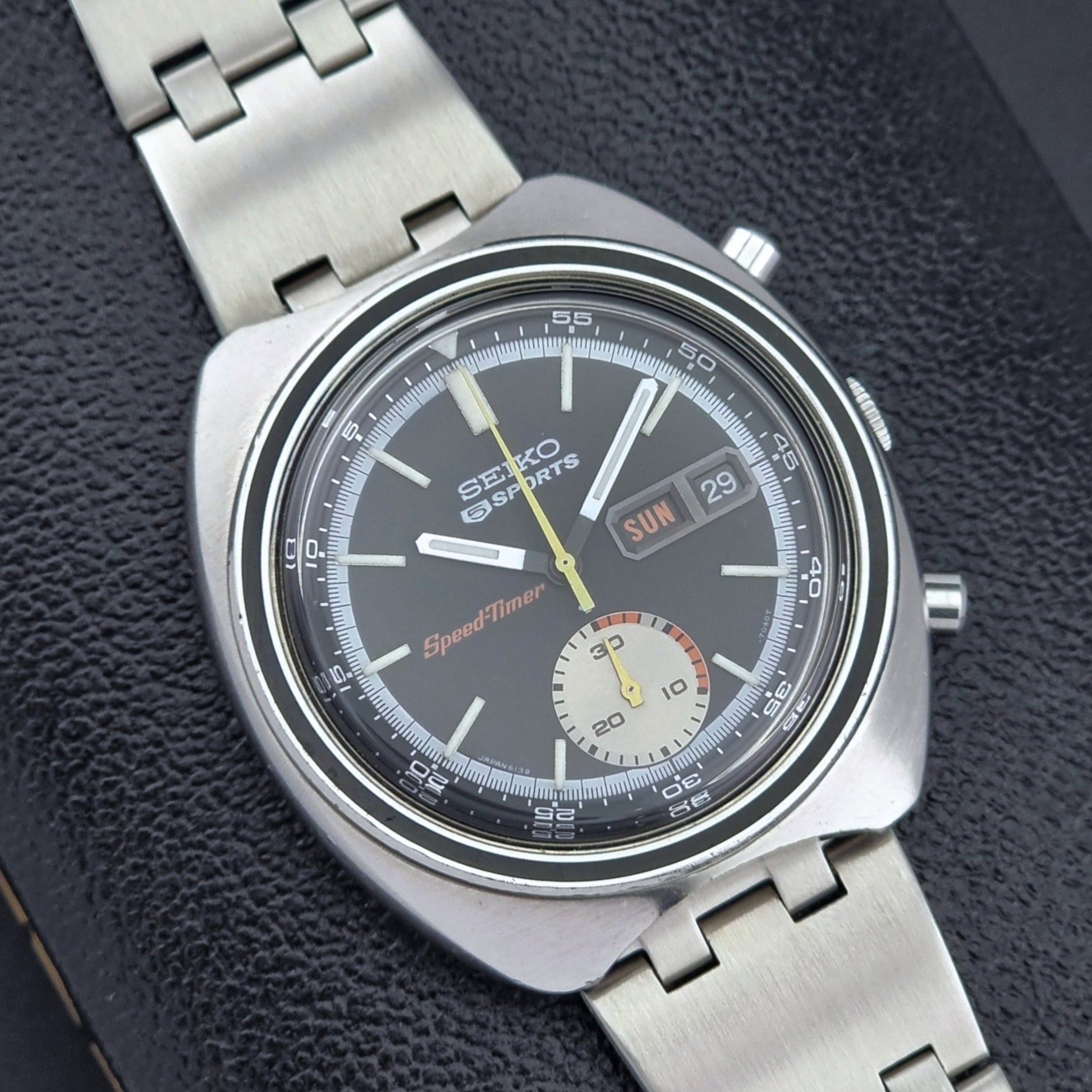 Vintage Seiko 5 sports Speedtimer 6139-7020 wristwatch with a dark face on a textured black background close up dial