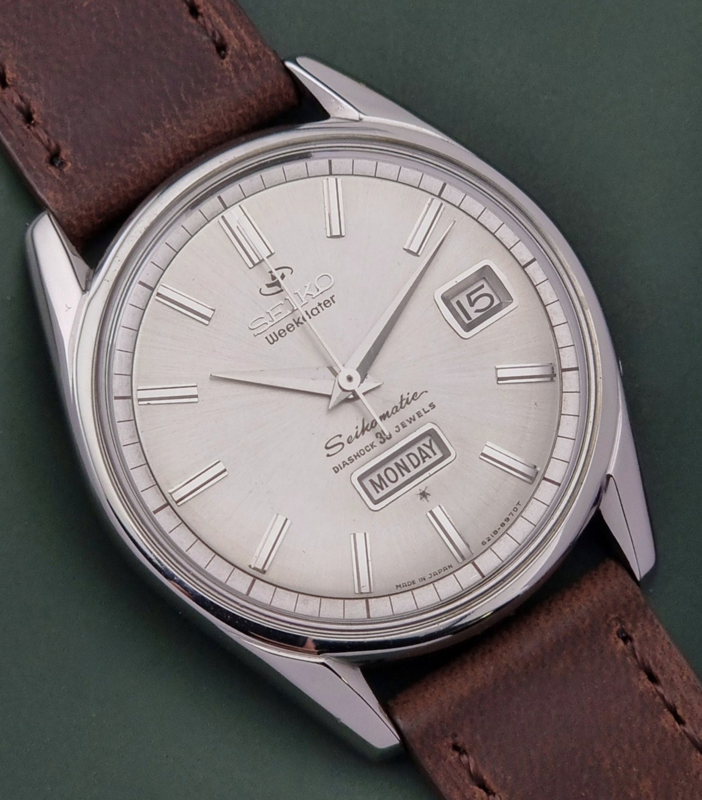 Seiko watch with brown leather strap on a green background