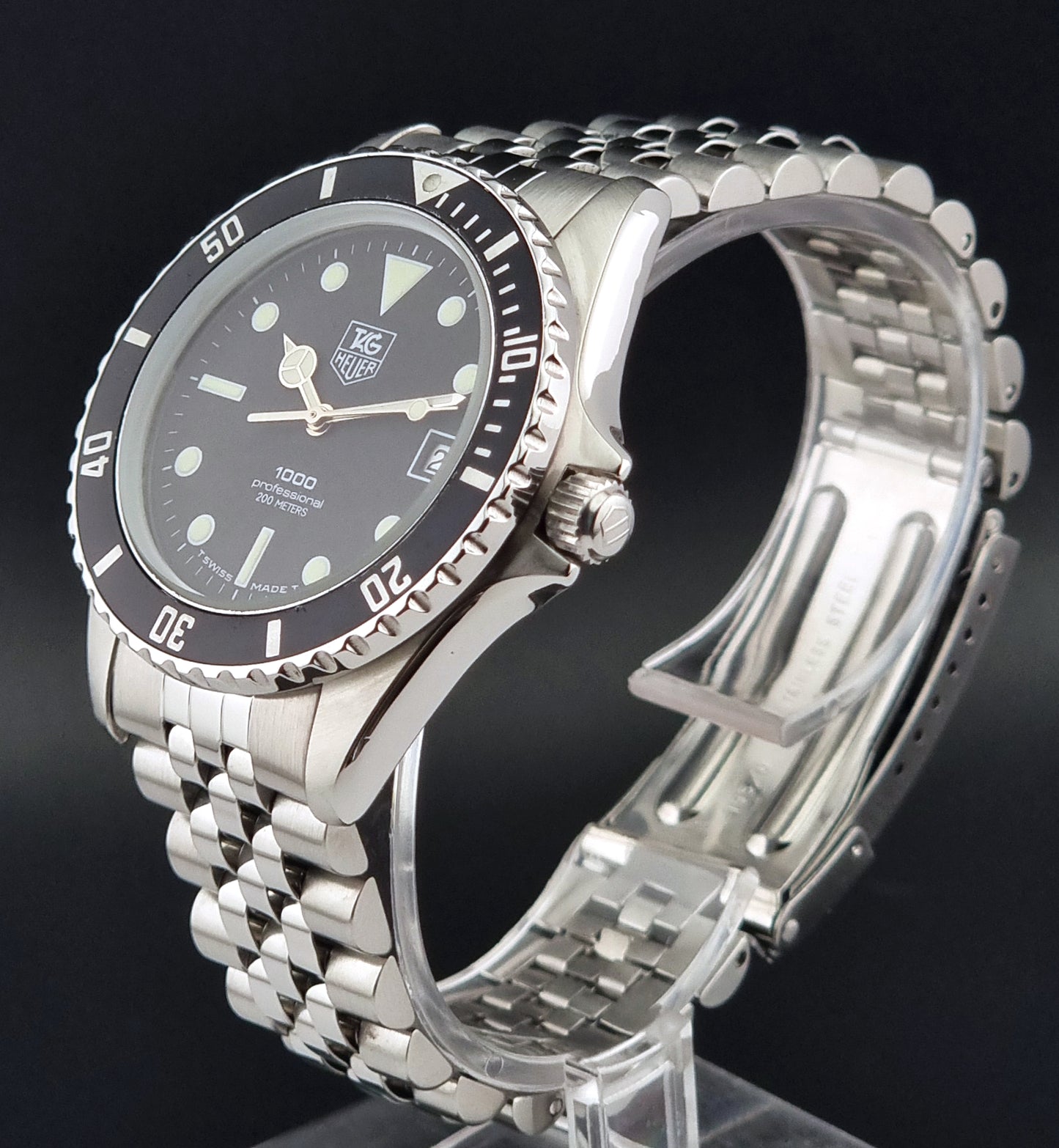 Vintage Tag Heuer Wristwatch Professional 1000 Quartz 980.013N with a black dial on a dark background close crown view