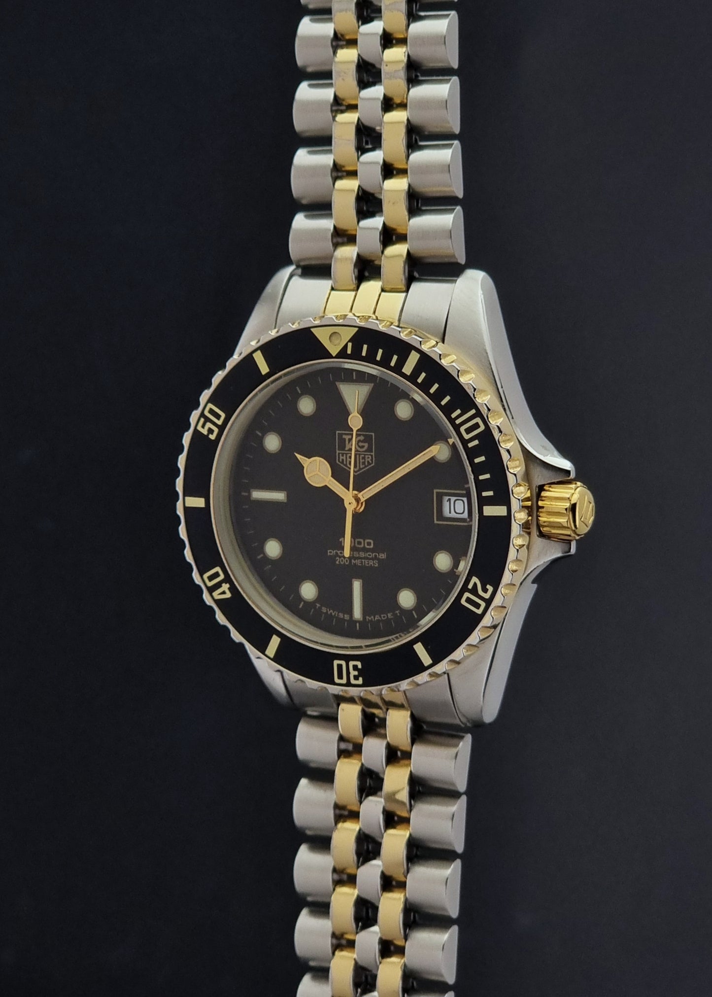 Vintage Tag Heuer watch Professional Quartz 1000 Diver 980.020N with silver and gold band on a dark background close crown view