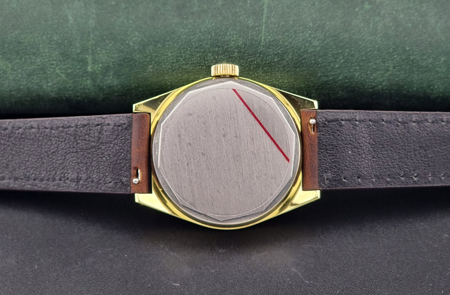 Vintage Tissot Watch 41620 PR 516 in Gold with brown leather strap on a green background case back view