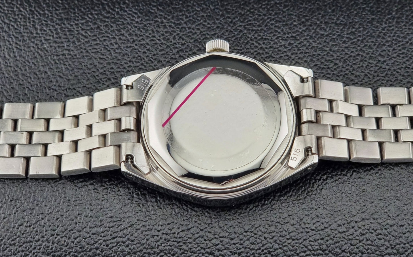 Tissot Seastar Visodate watch case back with a stainless band on a textured black background