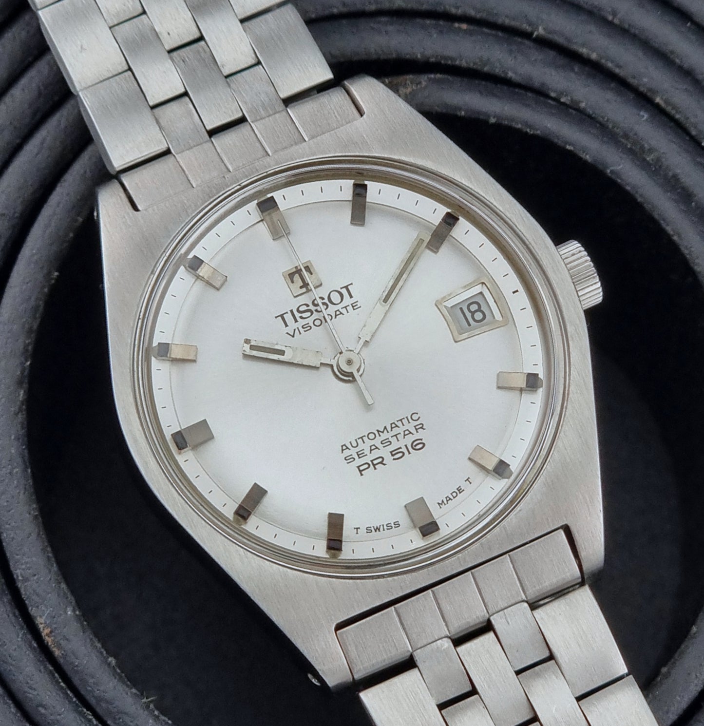 Tissot Seastar Visodate watch with white face on a dark textured background